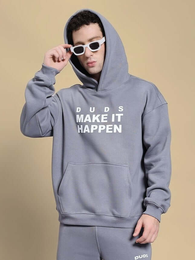Person wearing a grey MAKE IT HAPPEN FLEECE HOODIE, showcasing its design and fit.