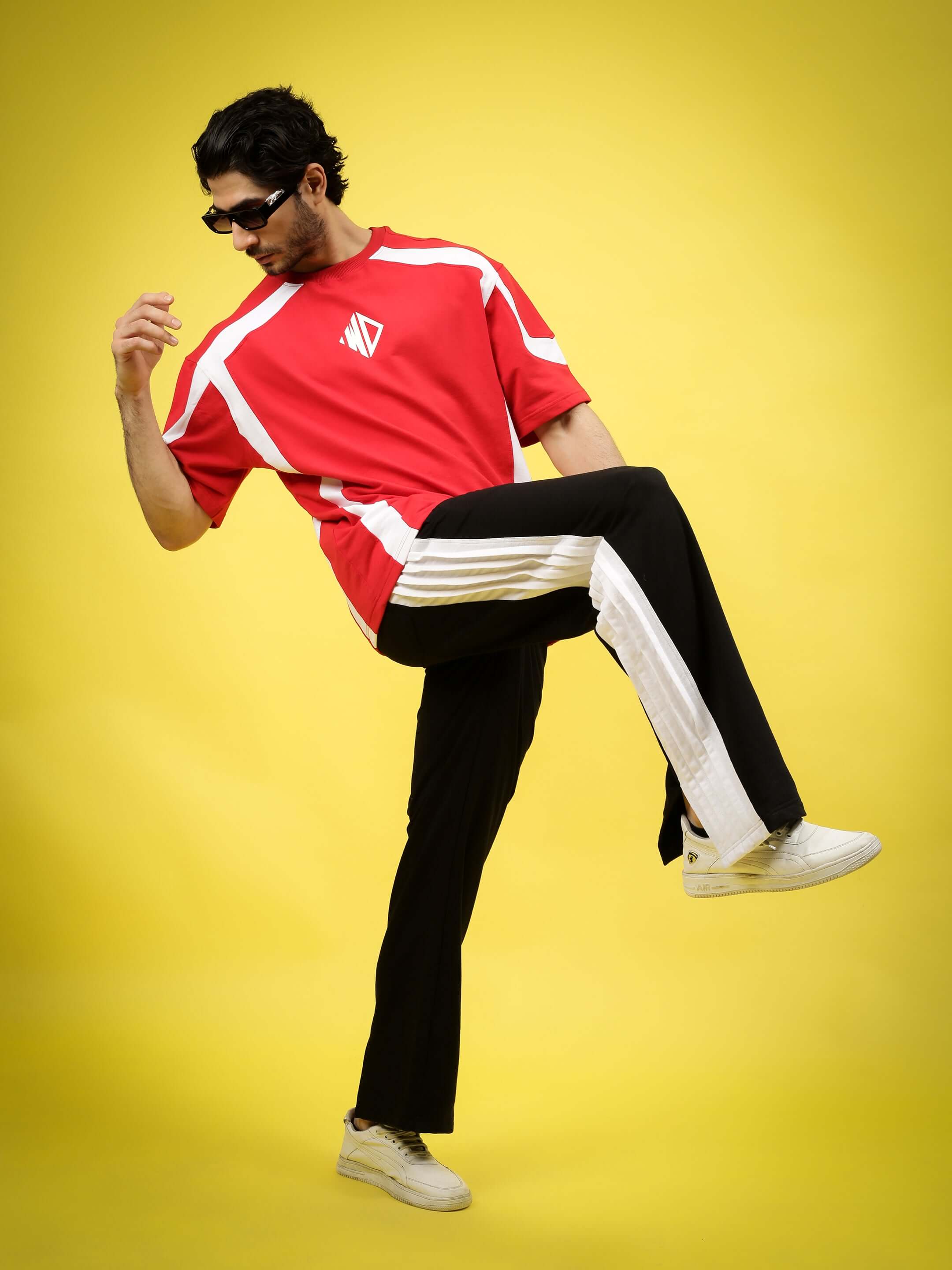 Man modeling Regal Baggy Joggers in black and white with a vibrant red shirt, set against a yellow background.