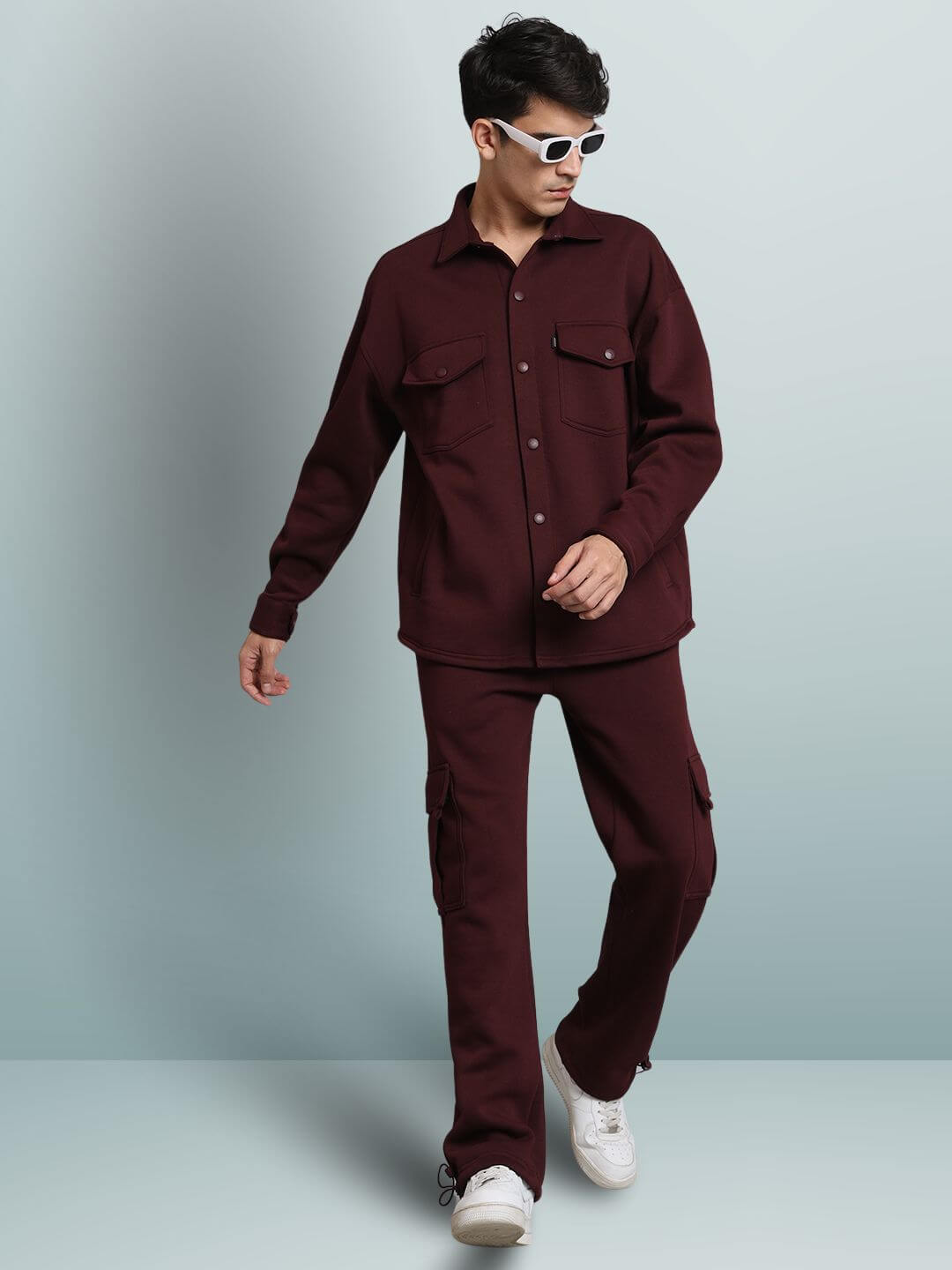 Model wearing maroon relaxed fit cargo fleece pants with matching shirt and white sneakers.