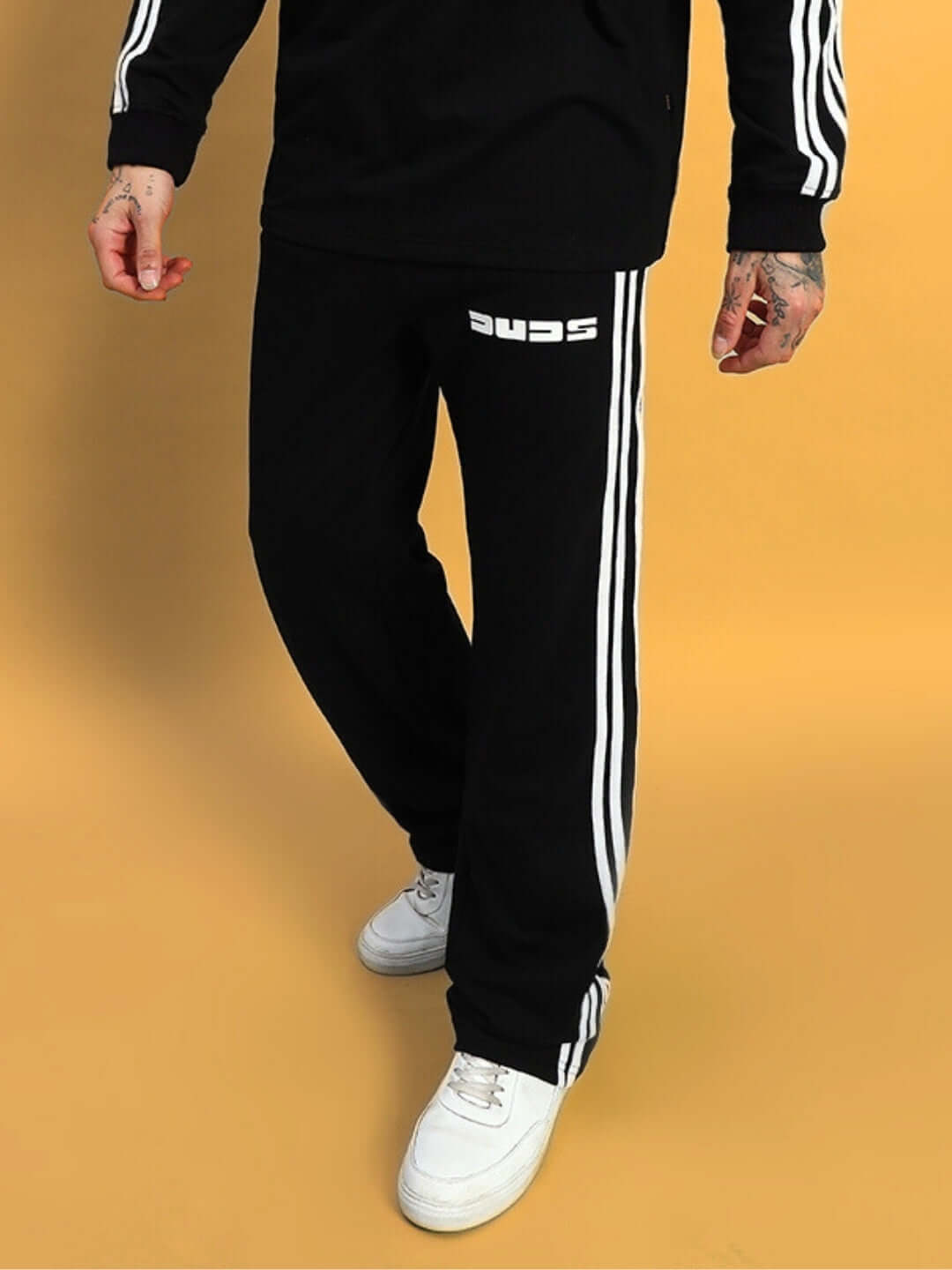 Model wearing black parka jogger pants with white stripes, featuring the brand logo, styled with white sneakers.
