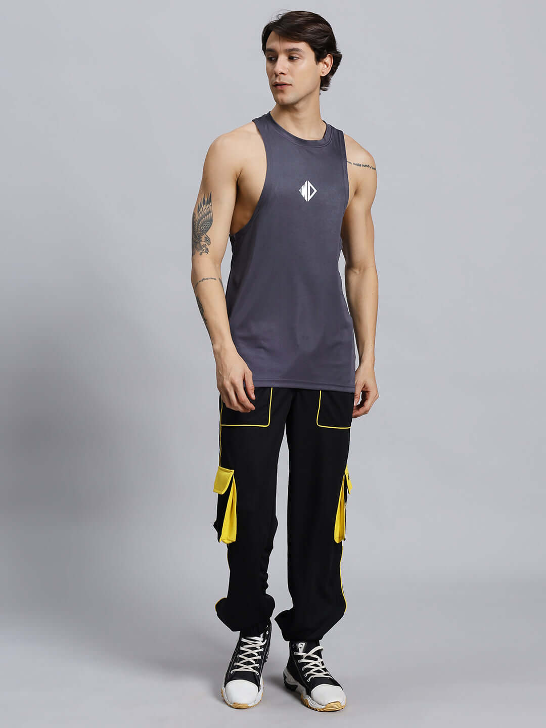 SOCCER REGULAR FIT CARGO JOGGER BLACKSOCCER REGULAR FIT CARGO JOGGER BLACK Man wearing black soccer regular fit cargo jogger with yellow accents and sleeveless grey shirt, posing against grey background.