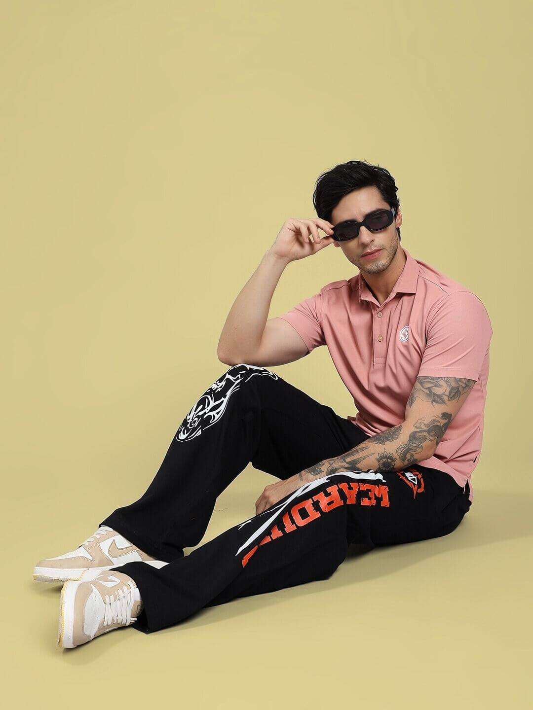 Man wearing RIFT RELAXED FIT JOGGER IN BLACK with a pink shirt, displaying casual and stylish outfit choices