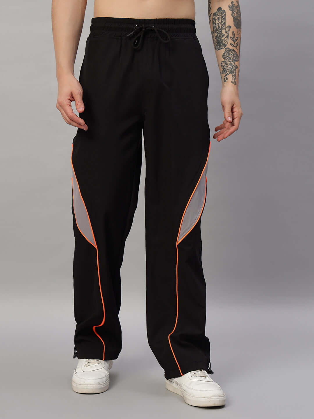 Unisex black oversized joggers with elastic waistband and drawstring, featuring orange accents; made from polyester parachute fabric.