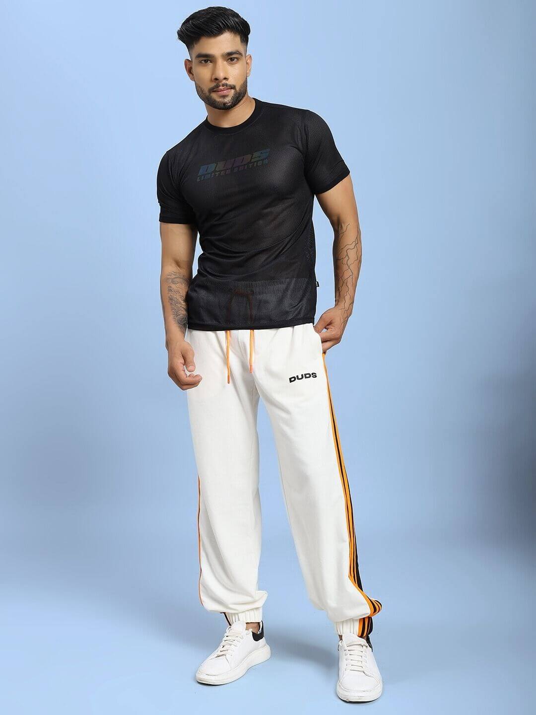 Model wearing COMFORT FLEX STRIPE JOGGER OFF-WHITE with vertical stripe detailing, paired with a black t-shirt in a relaxed pose.