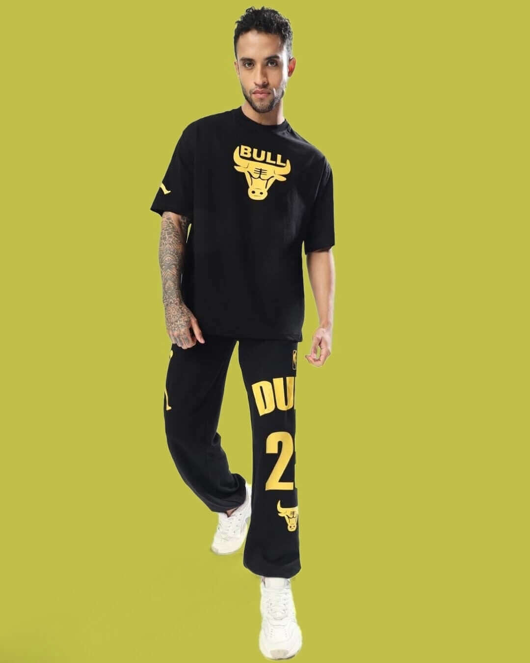 Model wearing black jogger set with bull graphics on a green background.