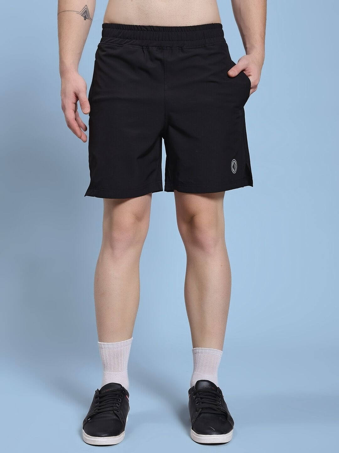 Man wearing black shorts against a blue background, showcasing casual sportswear style.