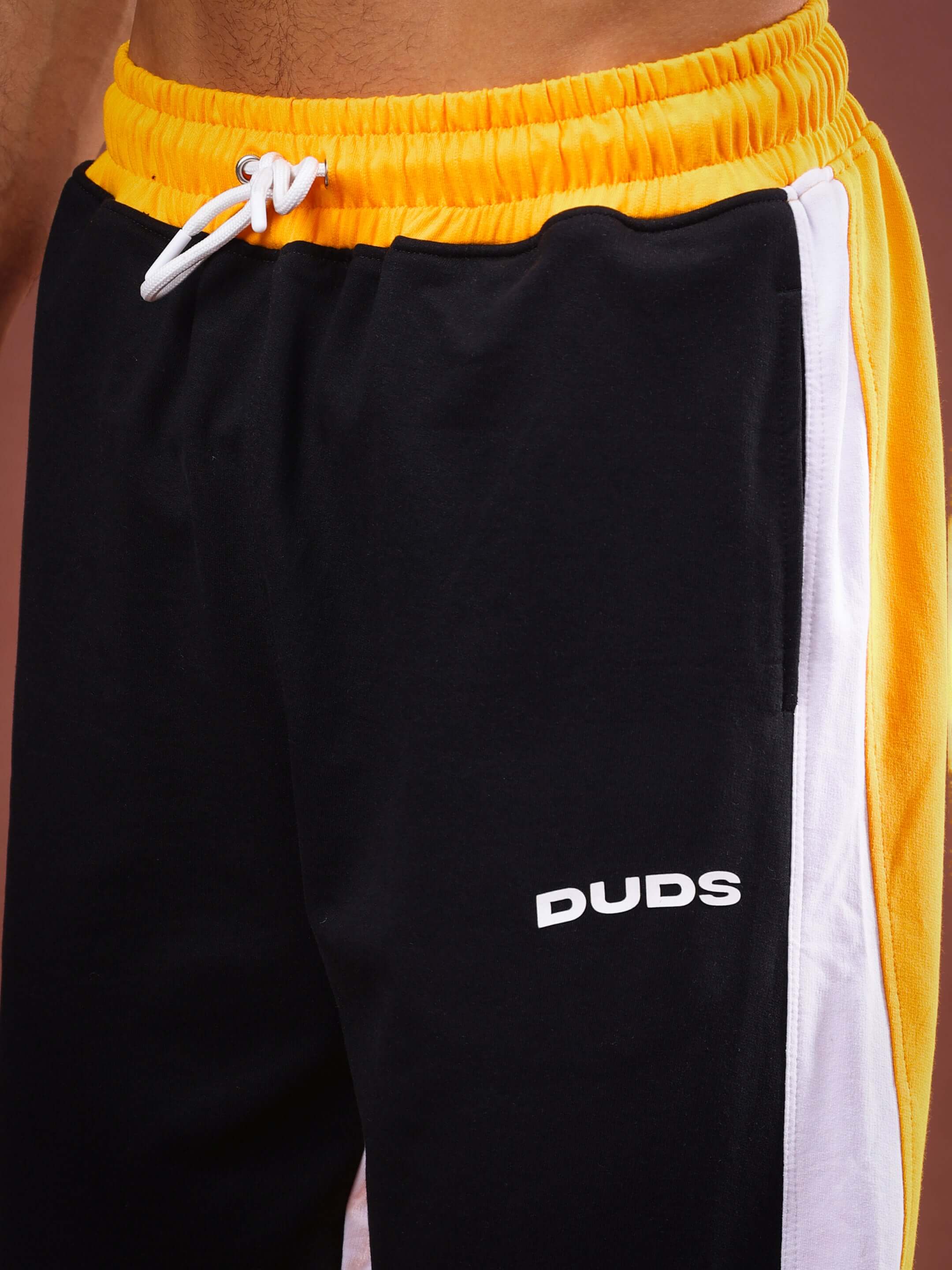 Close-up of Meraki Baggy Joggers in yellow and black by DUDS, featuring a drawstring waistband and custom fit option.