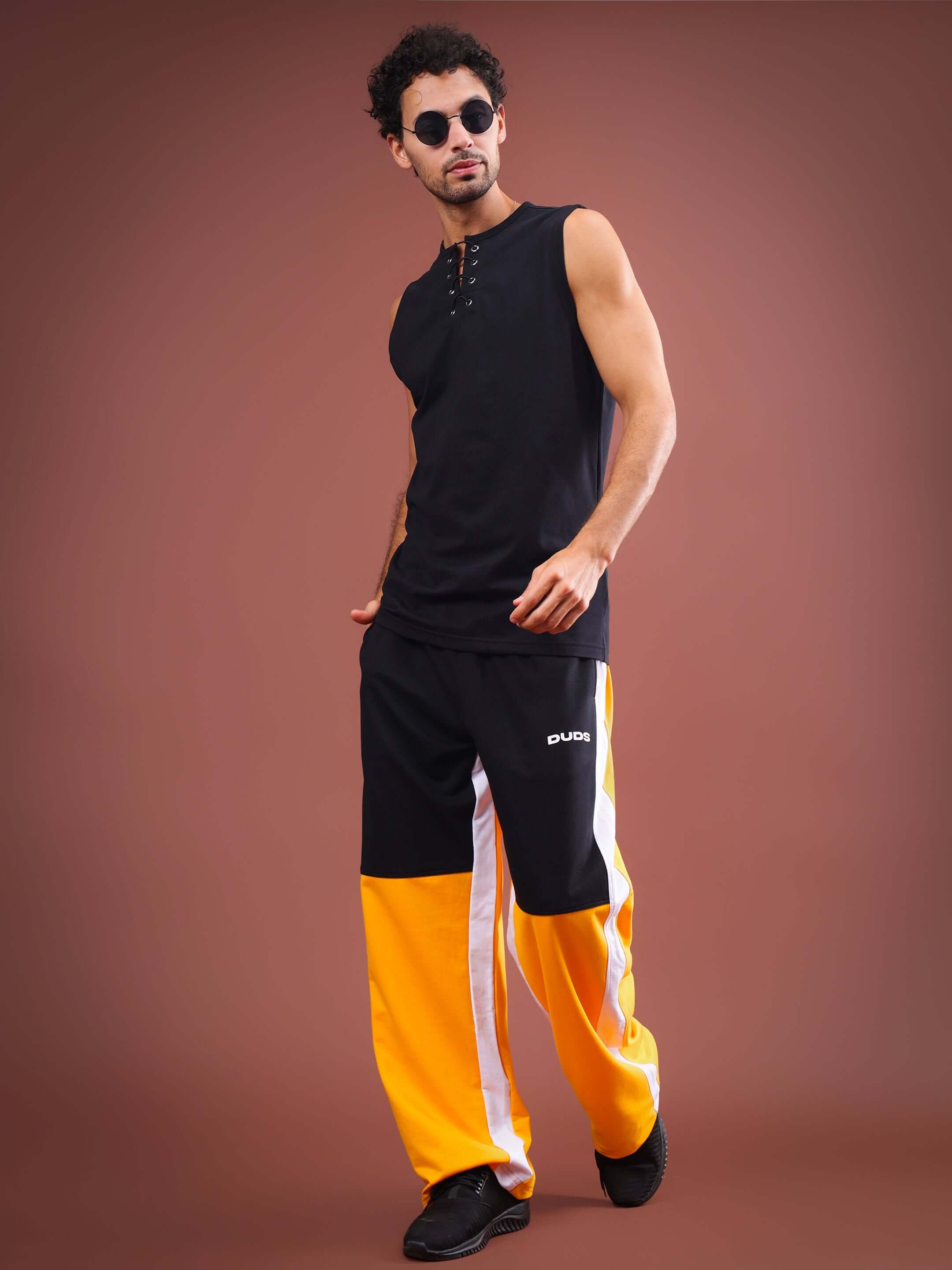 Man wearing MERAKI baggy joggers in yellow-black, showcasing stylish DUDS custom-fit athletic wear.