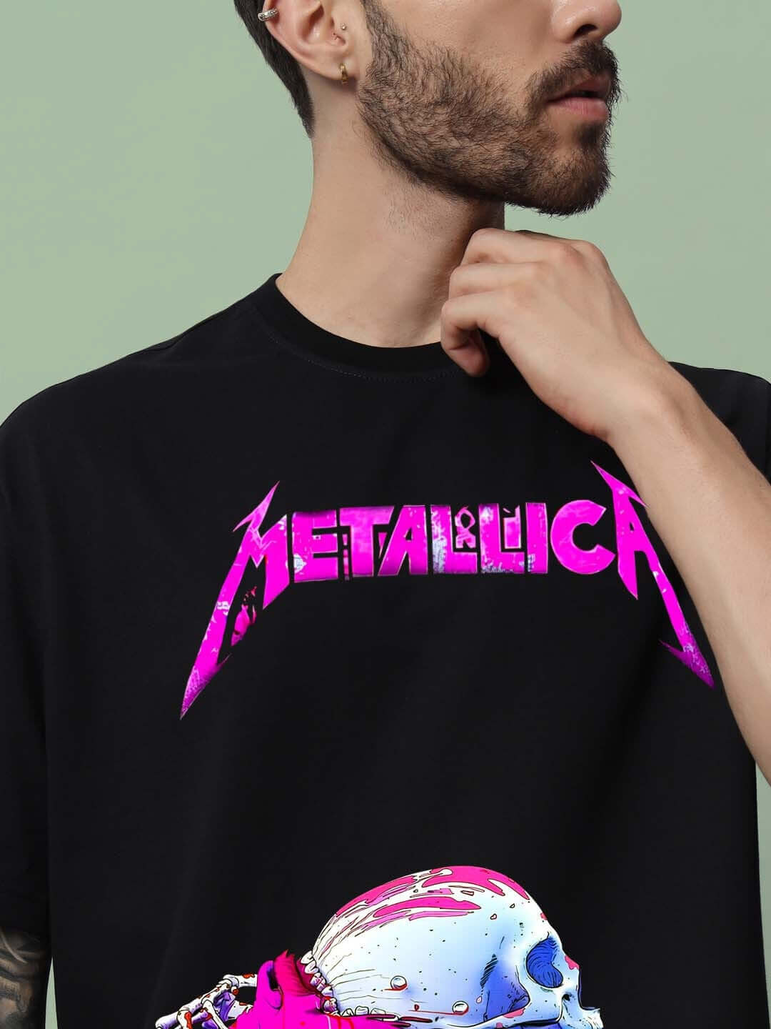 Man wearing a black oversized Metallica T-shirt with a vibrant pink logo, showcasing the graphic design and comfortable fit.