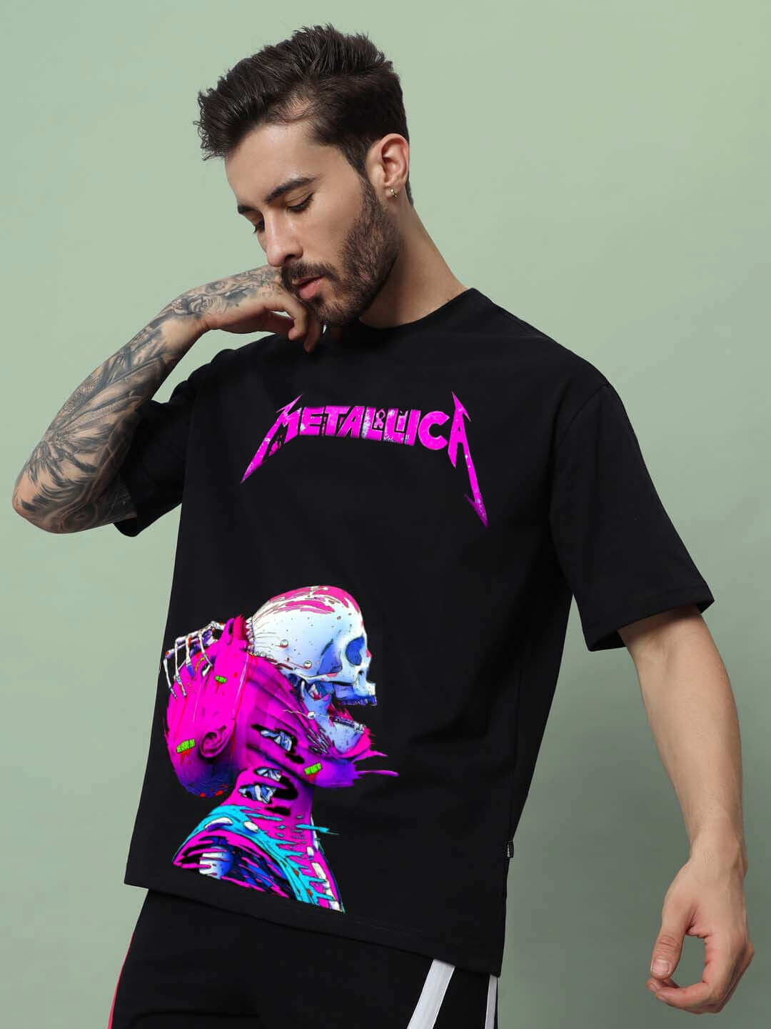 Man wearing oversized black Metallica t-shirt with vibrant graphic design, showcasing tattooed arm.