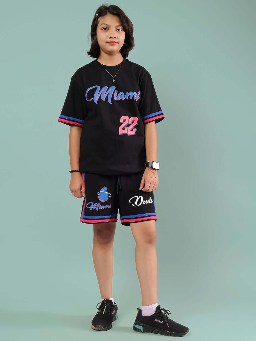Child wearing MIAMI CO-ORD FOR BOYS & GIRLS BLACK outfit, featuring black top and shorts with colorful trim. Suitable for customization.