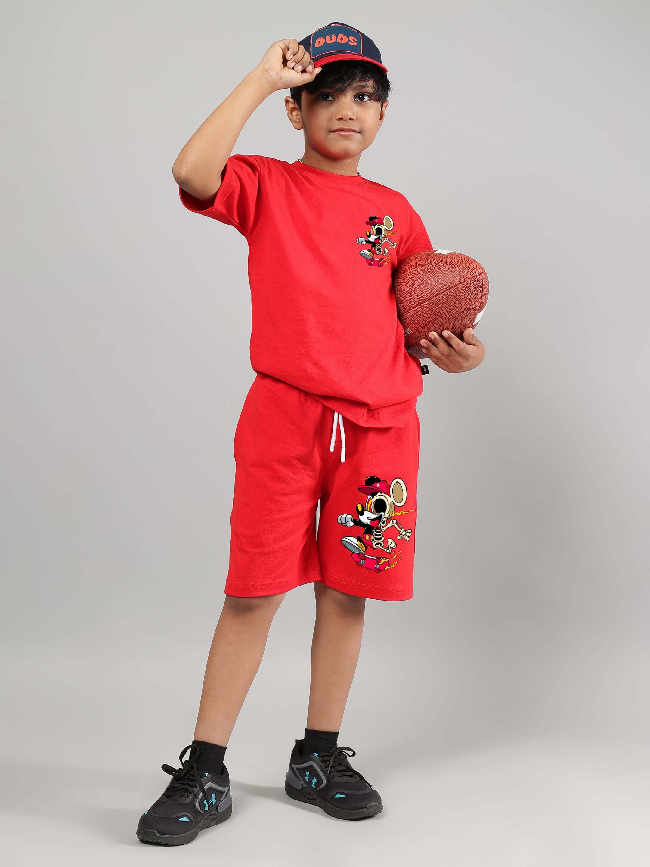 Boy wearing red Mickey summer shorts and t-shirt set with football, showcasing kids' custom fit clothing by DUDS.