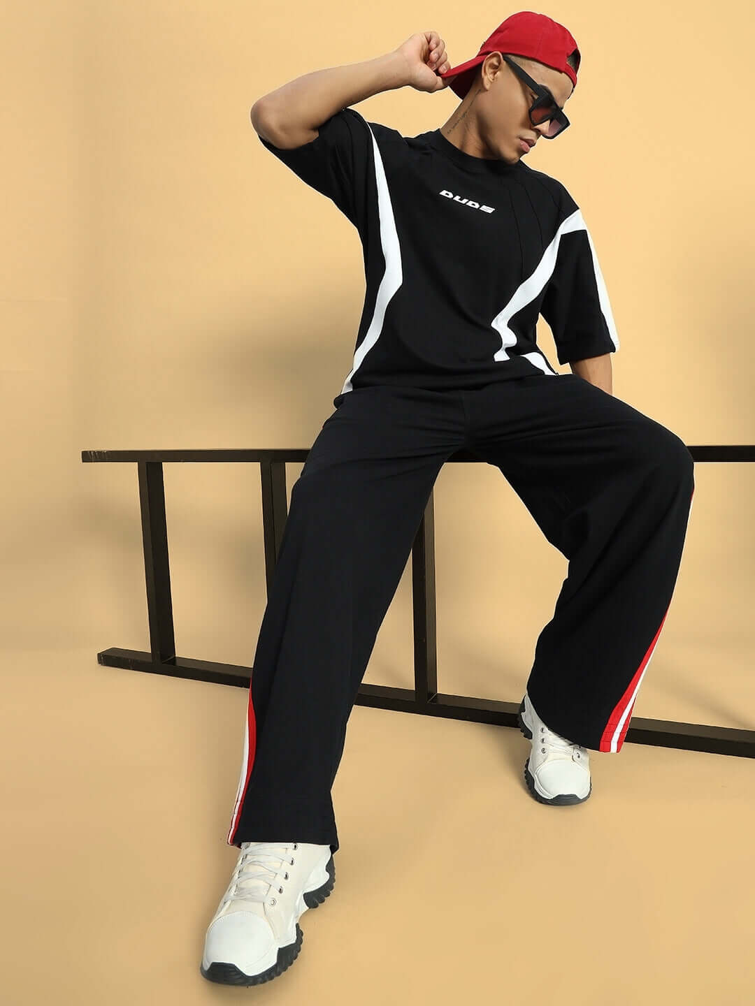 MILANO RELAXED-FIT COTTON JOGGERS BLACK-RED Model wearing DUDS MILANO relaxed-fit black joggers with red stripes, paired with a black t-shirt and white sneakers.