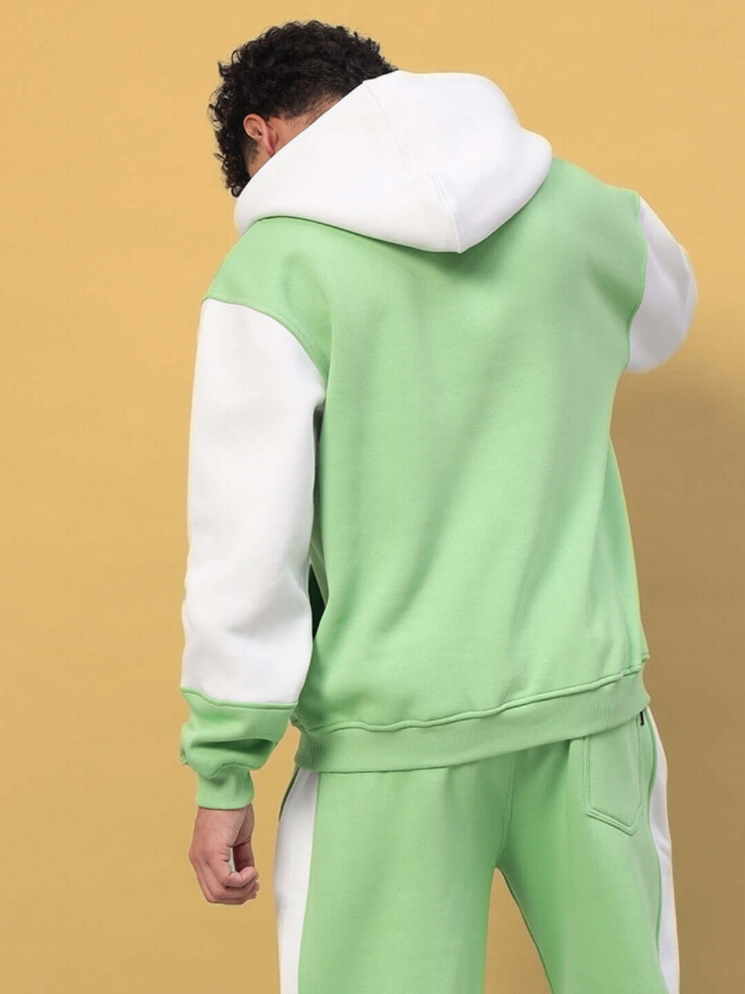 Back view of a man wearing a Minted Bliss colorblock hoodie in green and white.