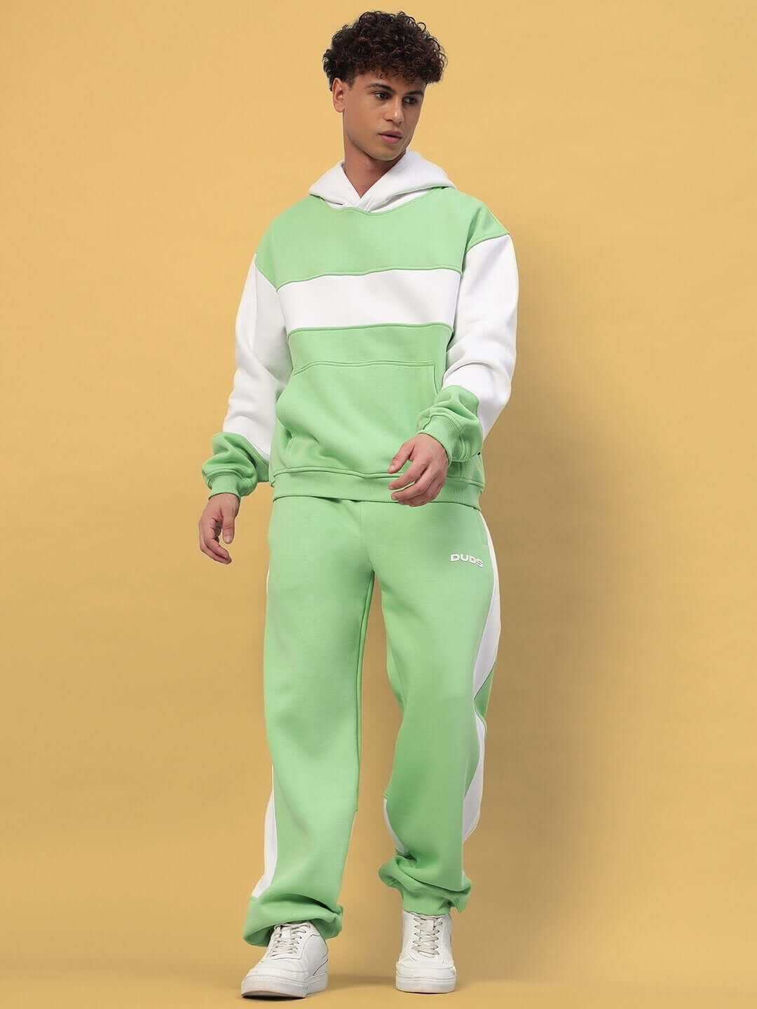 Man wearing MINTED BLISS FLEECE COLORBLOCK CO-ORD GREEN WHITE, showcasing green and white hoodie and joggers.