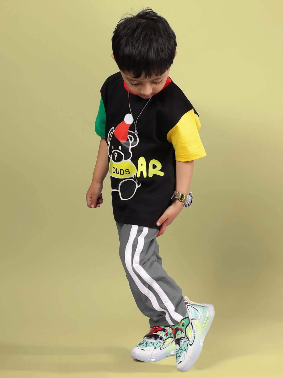 Child wearing MOCHA CO-ORD FOR BOYS & GIRLS BLACK GREY with colorful sneakers on a yellow background.