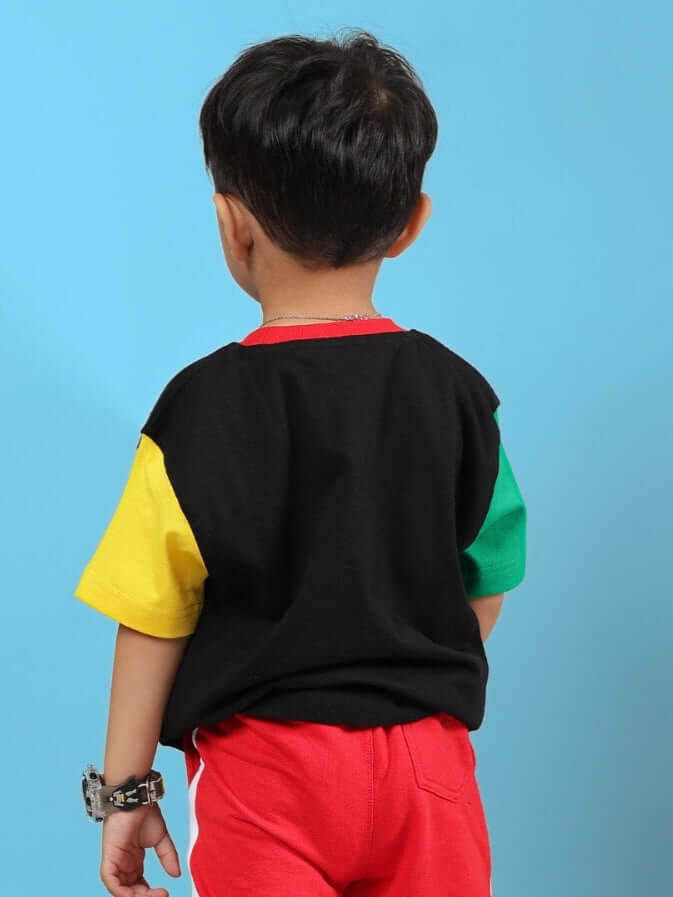 Child wearing MOCHA T-SHIRT FOR BOYS GIRLS BLACK with colorful sleeves, shown from the back, against a blue background.