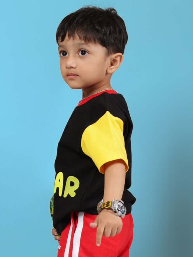 Young child wearing MOCHA T-SHIRT FOR BOYS GIRLS BLACK with colorful sleeves and a watch, standing against a blue background.
