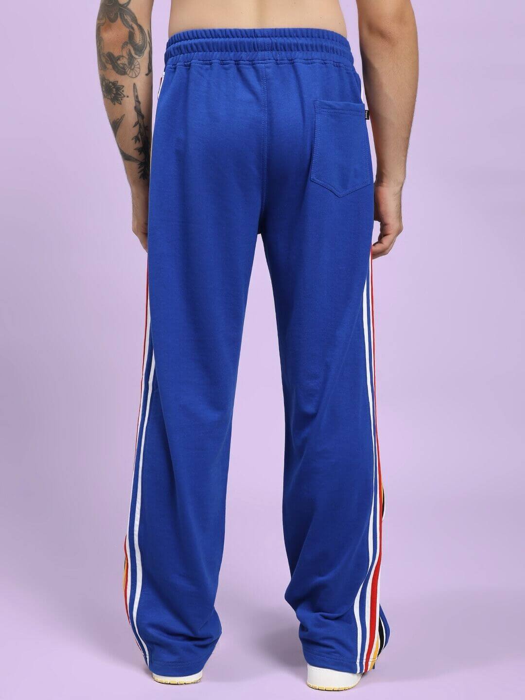 MODERN EDGE MULTI-STRIPE JOGGER ROYAL BLUE Blue track pants with side stripes worn by a person on a light purple background
