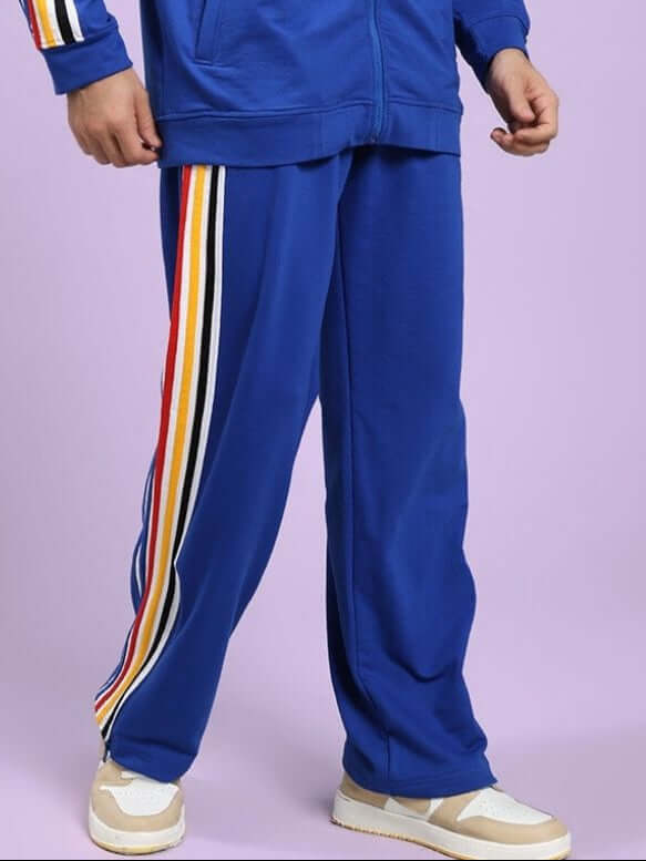 MODERN EDGE MULTI-STRIPE JOGGER ROYAL BLUE Man wearing a blue tracksuit with colorful stripes on a light purple background