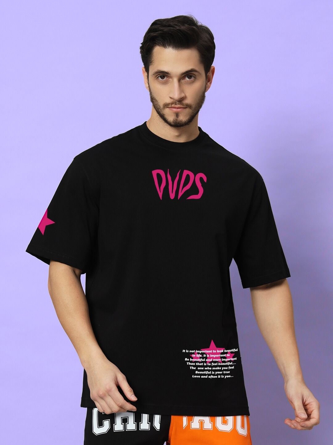 Model wearing MODERN LOVE OVER-SIZED T-SHIRT BLACK, featuring bold graphic design, against purple background.