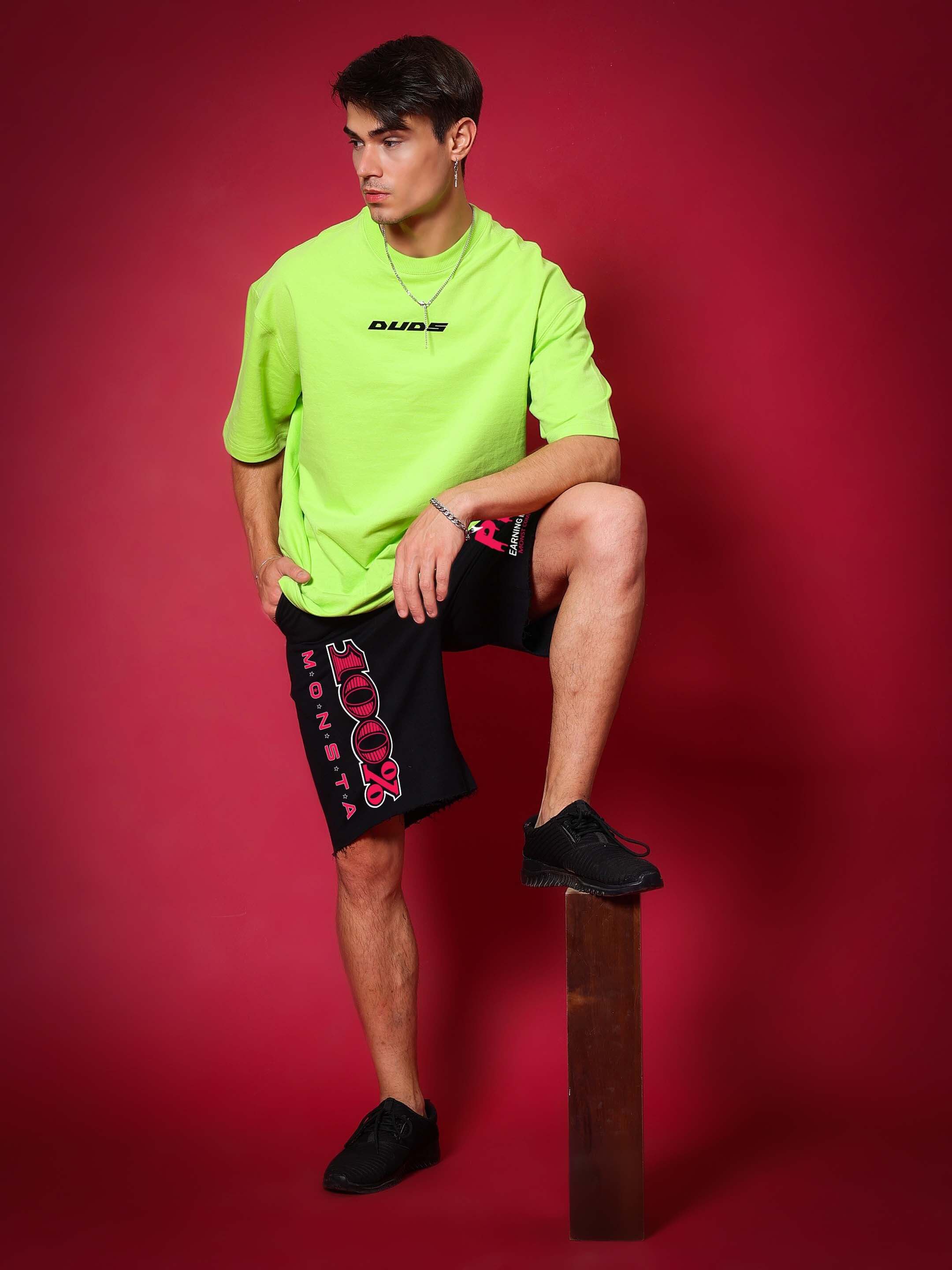 Model wearing Monsta Combat Regular Fit Shorts Black with green shirt, showcasing style and durability for workouts and outdoor activities.