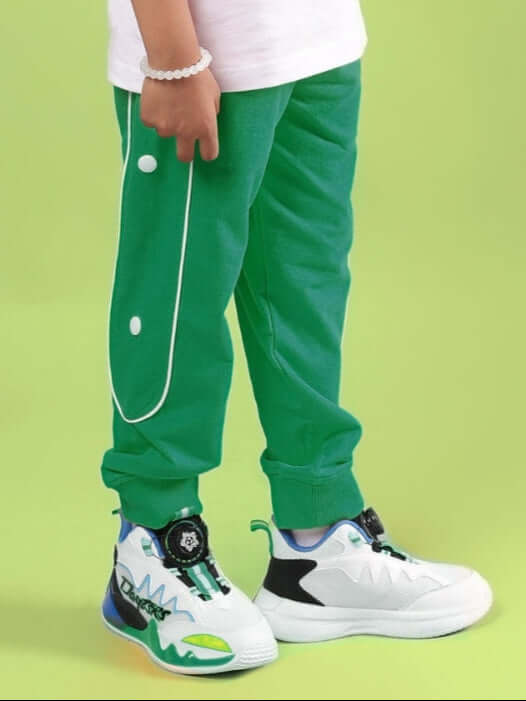 Child wearing MOON NIGHT JOGGER FOR BOYS & GIRLS GREEN with stylish shoes on a green backdrop