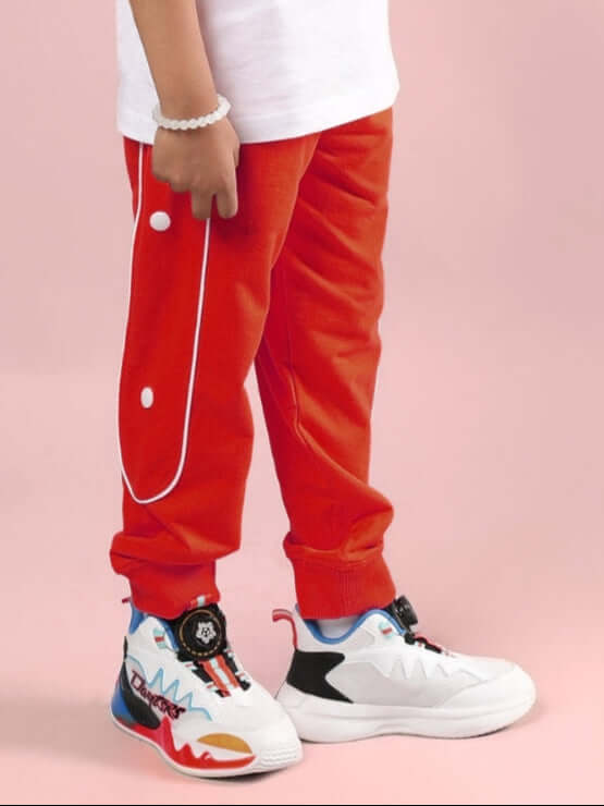 MOON NIGHT JOGGER FOR BOYS & GIRLS RED by WEAR DUDS, stylish and comfortable red joggers for kids on white shoes, side view.
