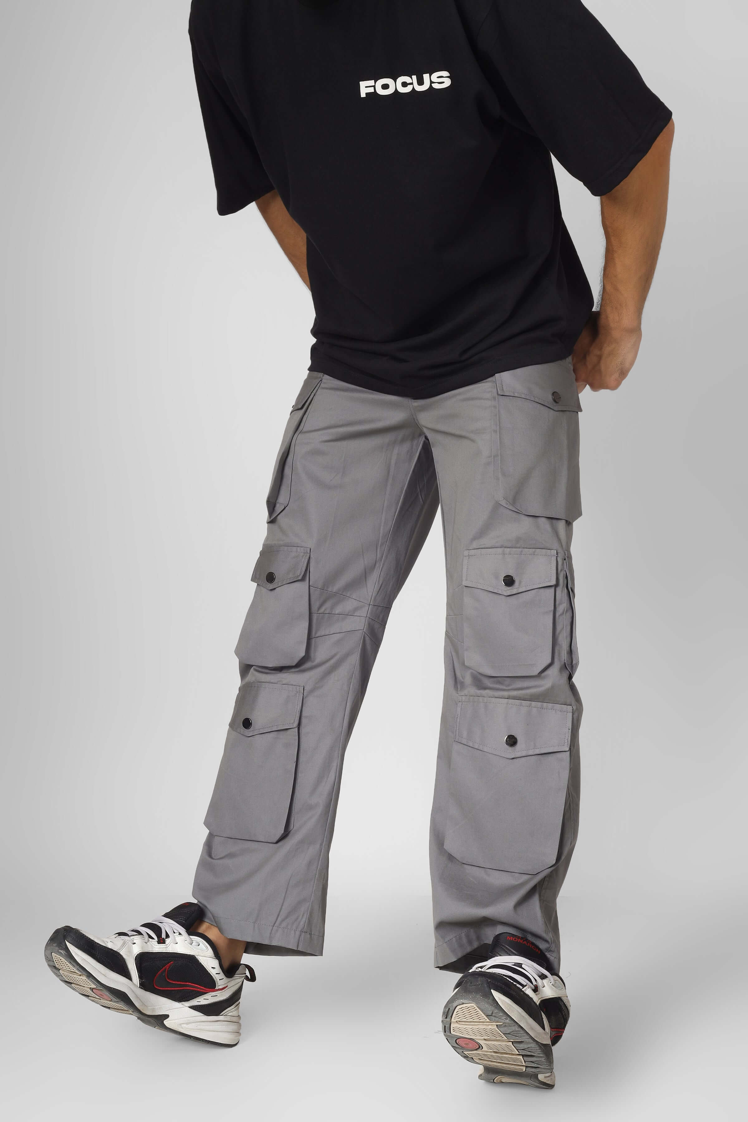 Model wearing Moon Stone cargo pants with 12 pockets, tailored by DUDS, shown with casual sneakers and black T-shirt.
