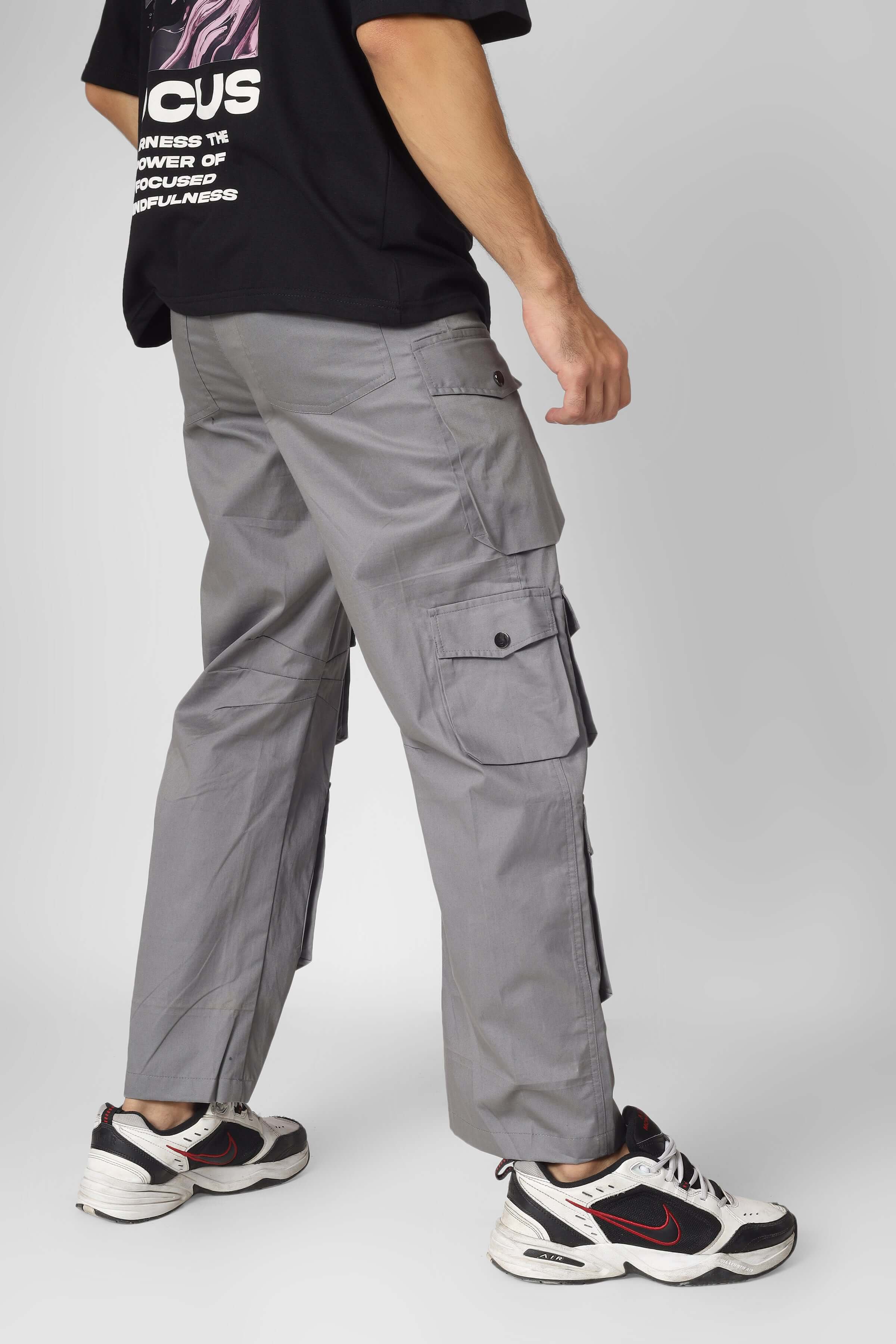 Model wearing Moon Stone Cargo Pants with 12 pockets, gray color, paired with sneakers, displayed in a side profile.