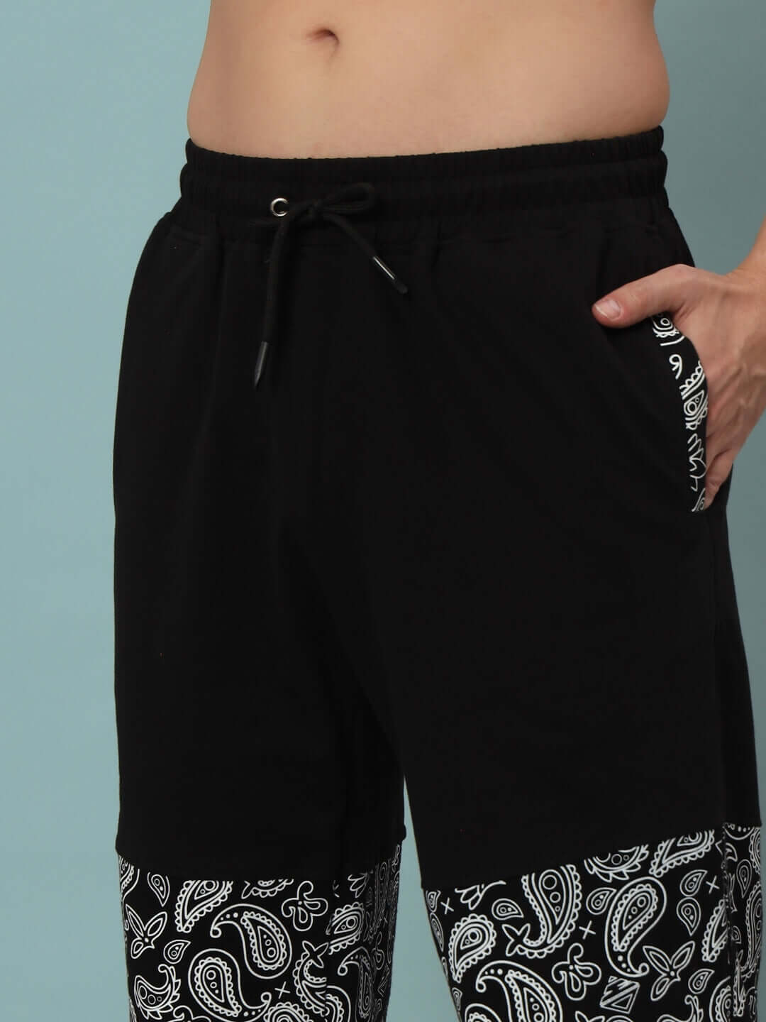 Close-up of MOSAIC BAGGY JOGGERS in black with paisley design, featuring a drawstring waist and side pocket detail.