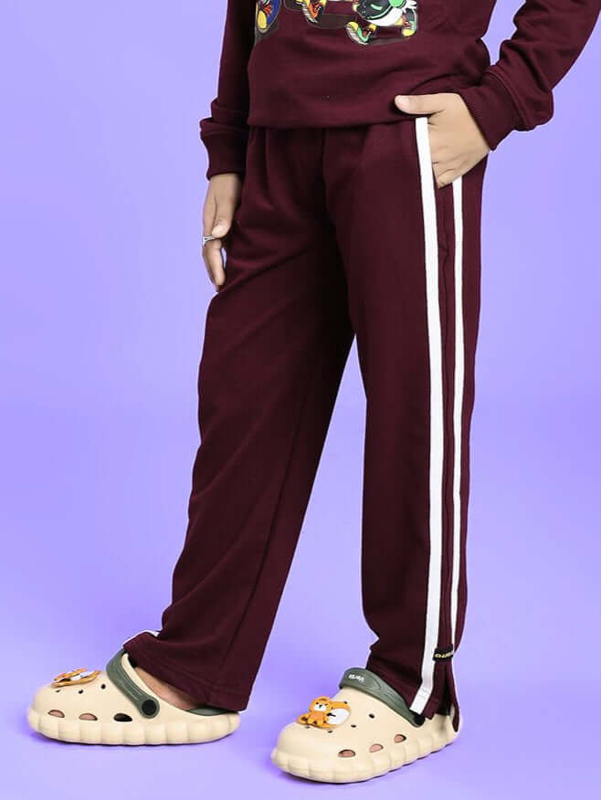 Child wearing MOSCOW RELAXED FIT JOGGER FOR BOYS AND GIRLS MAROON with side stripes on a purple background.