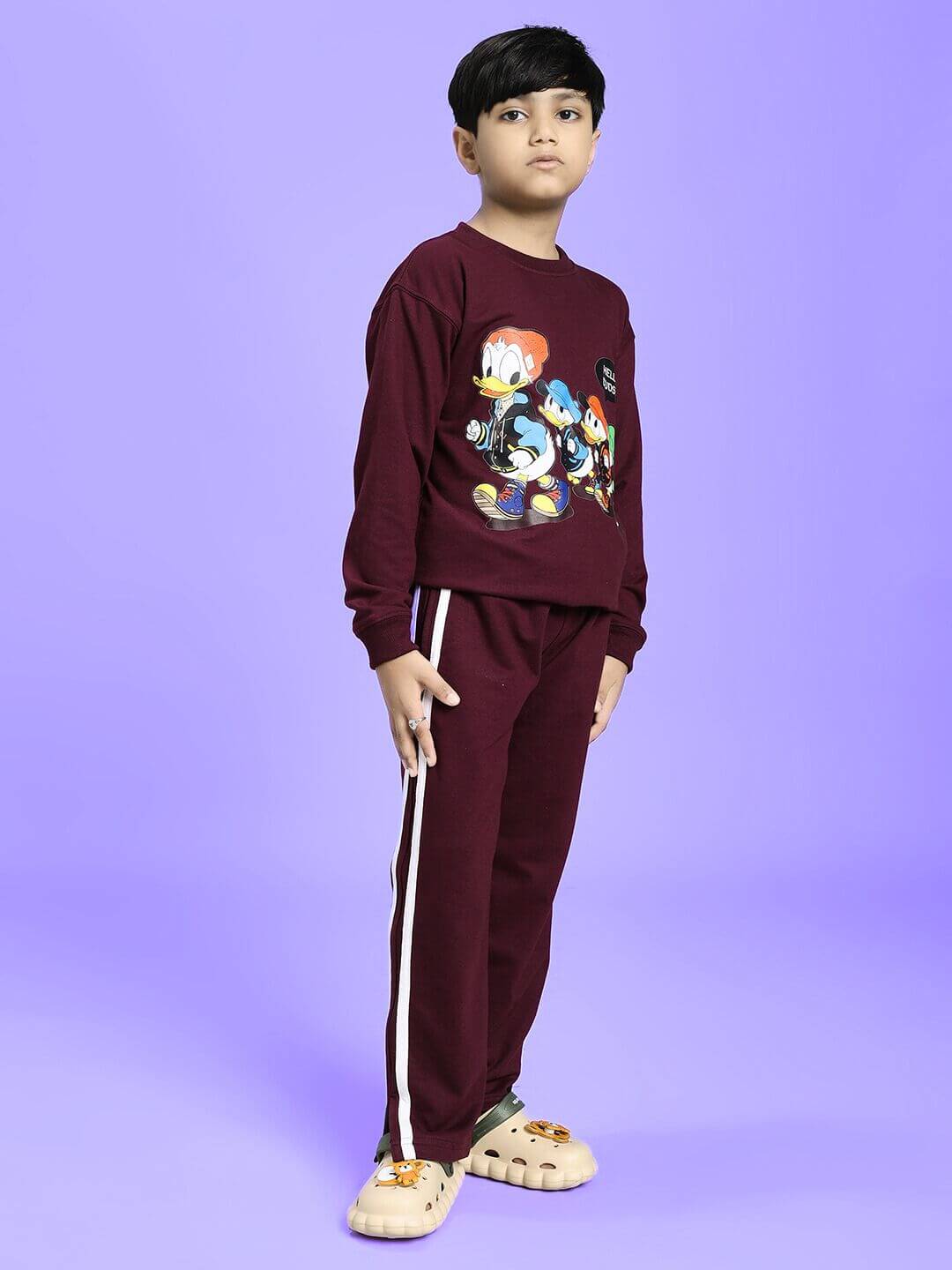 Boy wearing MOSCOW RELAXED FIT JOGGER FOR BOYS AND GIRLS MAROON, standing against a purple background.