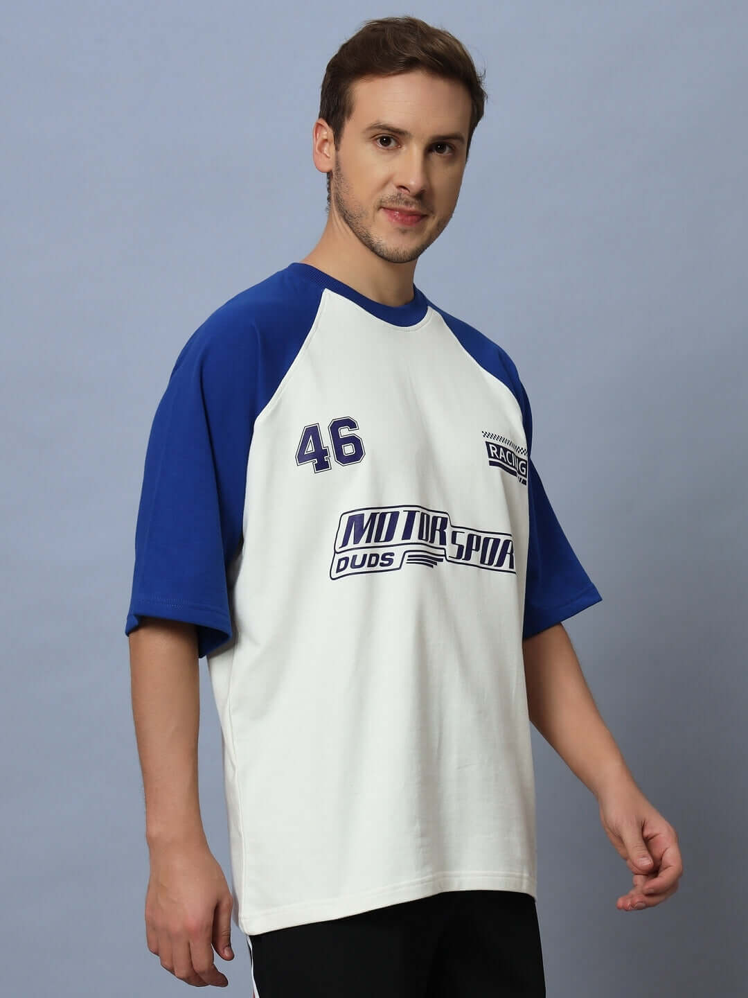 Man wearing oversized off white and blue motor sport raglan t-shirt featuring premium cotton fabric and sporty logo design.