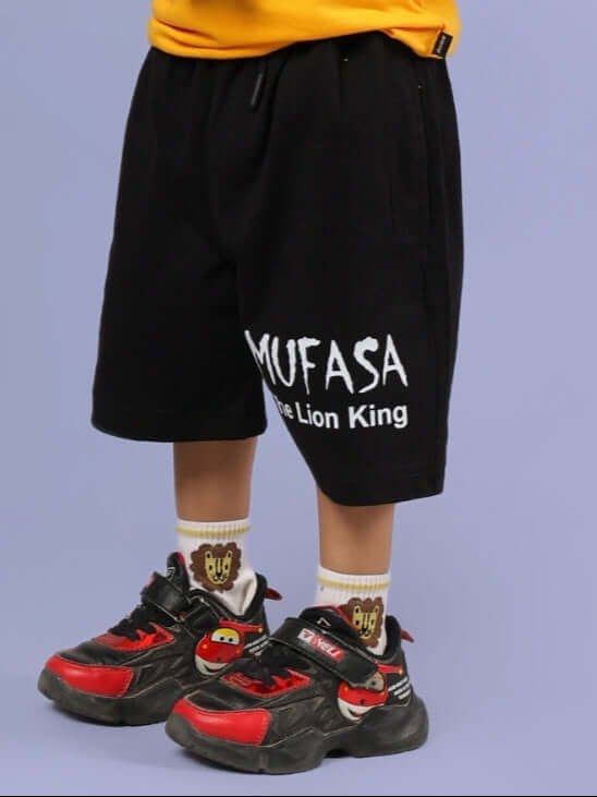 Child wearing MUFASA SHORTS FOR BOYS & GIRLS BLACK with sneakers, showcasing trendy fashion.