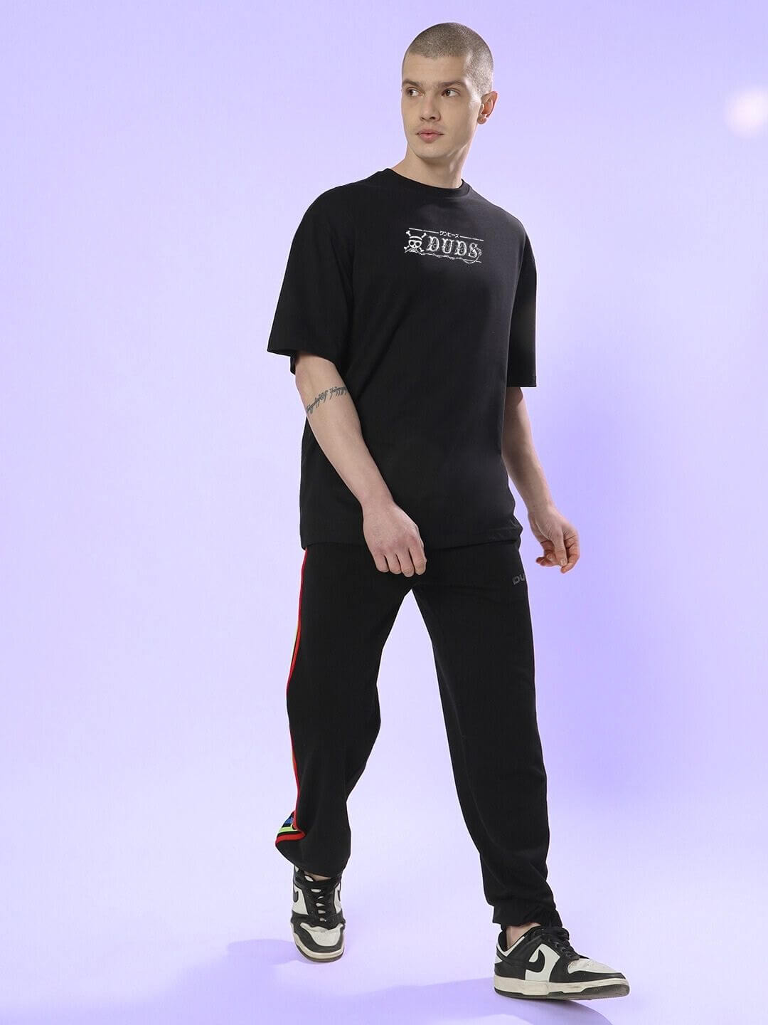 Man wearing Mugiwara Printed Oversized T-Shirt Black with casual streetwear style on a purple background.