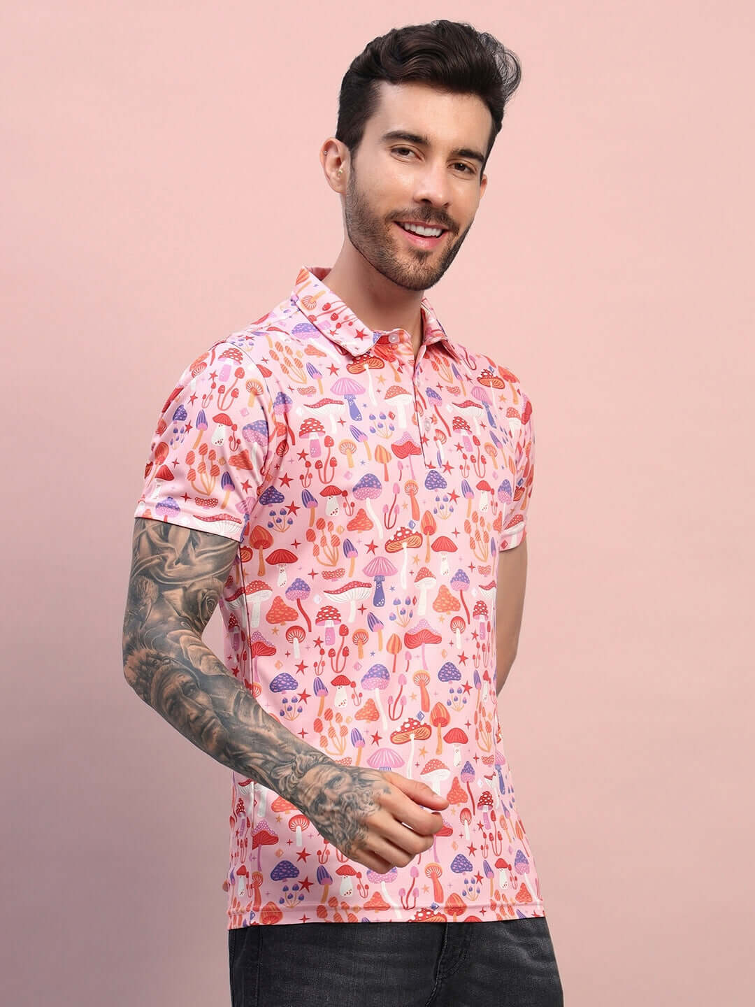 Man wearing pink multi-colored mushroom print t-shirt in sports polyester fabric. Stylish casual wear for a trendy look.