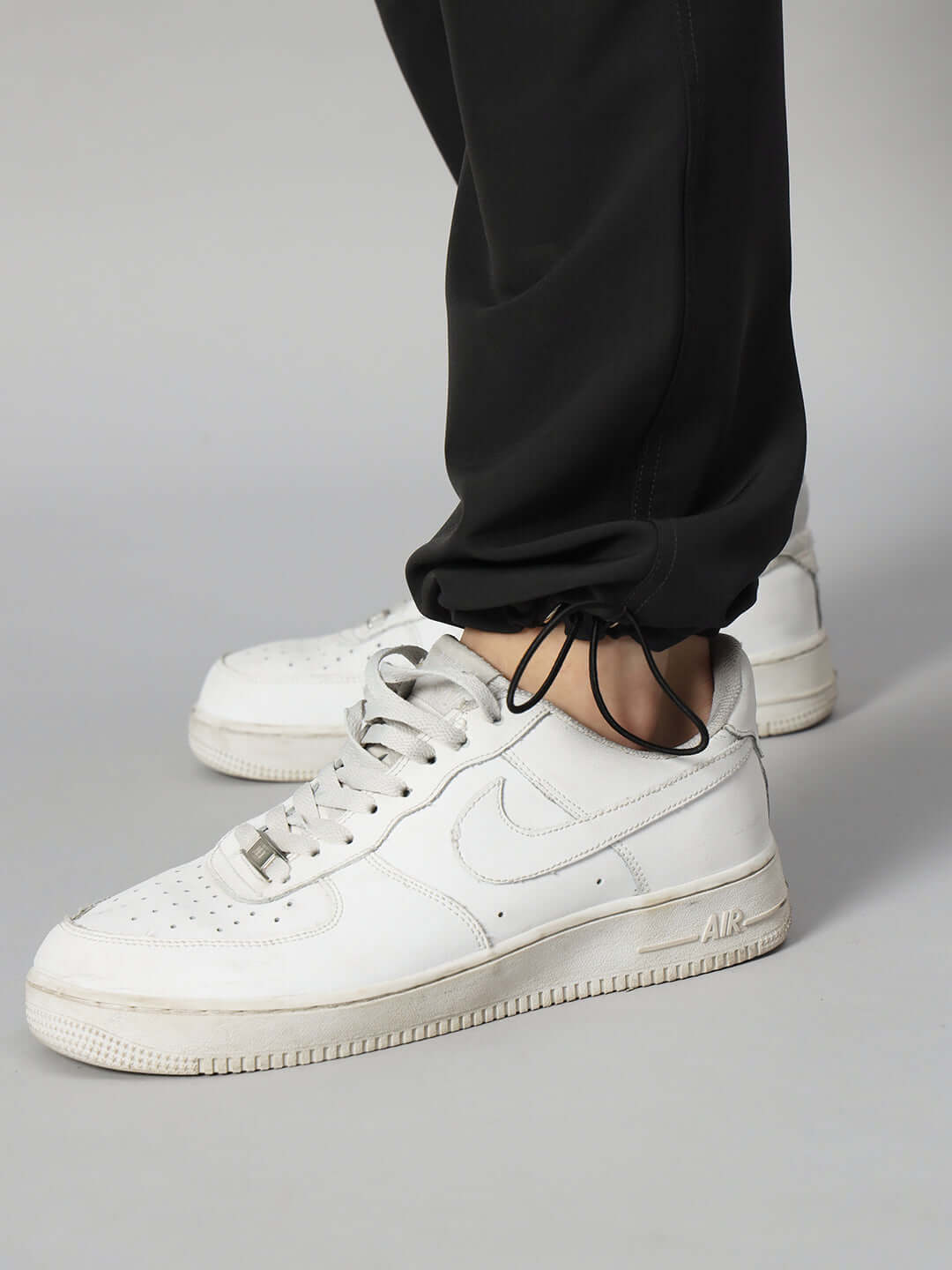 Close-up of Myriad Relaxed Fit Cargo Pants in black, paired with white sneakers, showcasing adjustable ankle fit for customized wear.