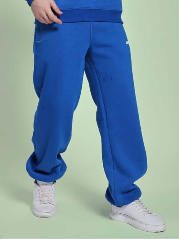 Person wearing NATURE LINK FLEECE JOGGER ROYAL BLUE showcasing vibrant blue joggers with white sneakers.