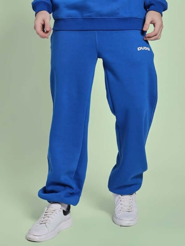Man wearing NATURE LINK FLEECE JOGGER ROYAL BLUE with white sneakers, showcasing cozy and stylish loungewear for indoor or outdoor use.