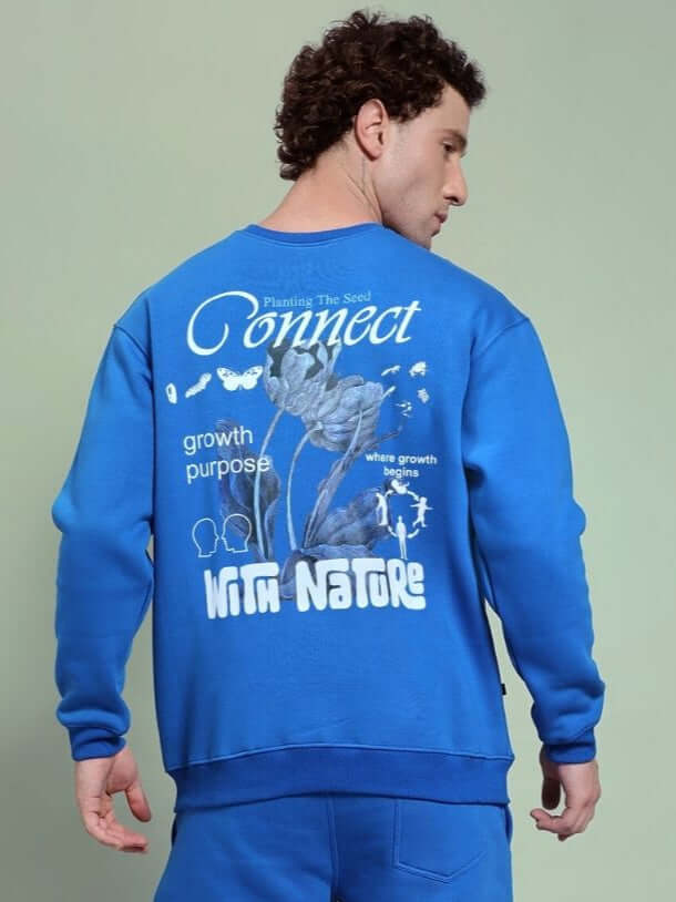 Man wearing NATURE LINK FLEECE SWEATSHIRT ROYAL BLUE with nature-inspired back design, ideal for comfort and style.
