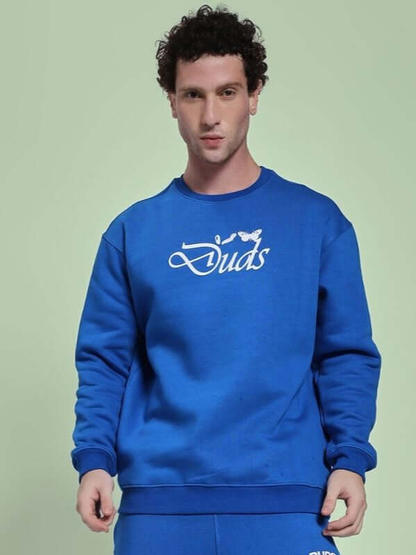 Man wearing NATURE LINK FLEECE SWEATSHIRT ROYAL BLUE in casual setting, showcasing cozy fleece fabric and vibrant royal blue color.