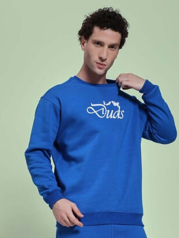 Man wearing NATURE LINK FLEECE SWEATSHIRT ROYAL BLUE, holding the sweatshirt collar, showcasing the vibrant royal blue color and cozy design.