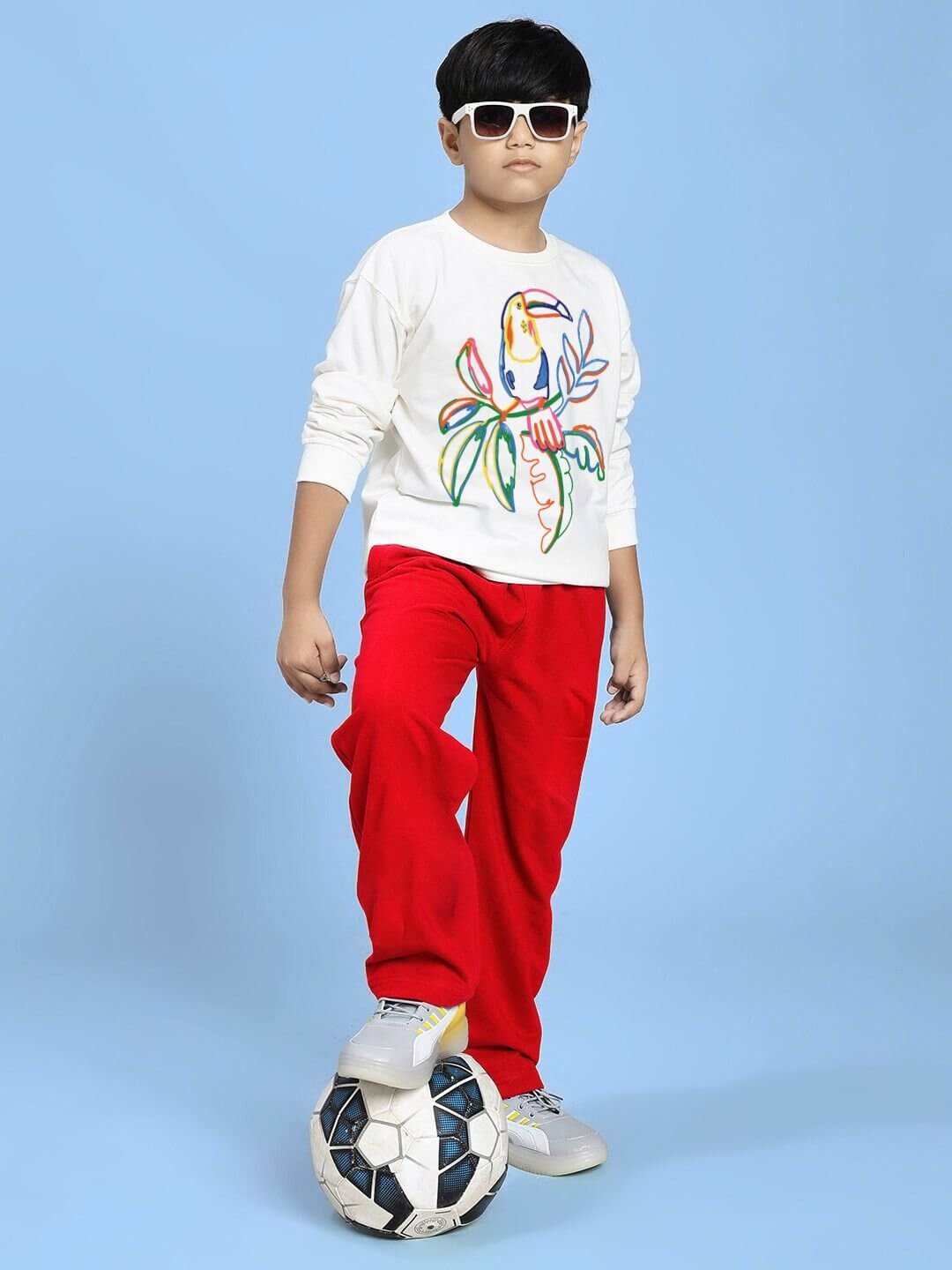 Boy wearing NATURE VIBES BIRD PRINT CO-ORD FOR BOYS AND GIRLS WHITE RED with sunglasses and soccer ball on blue background