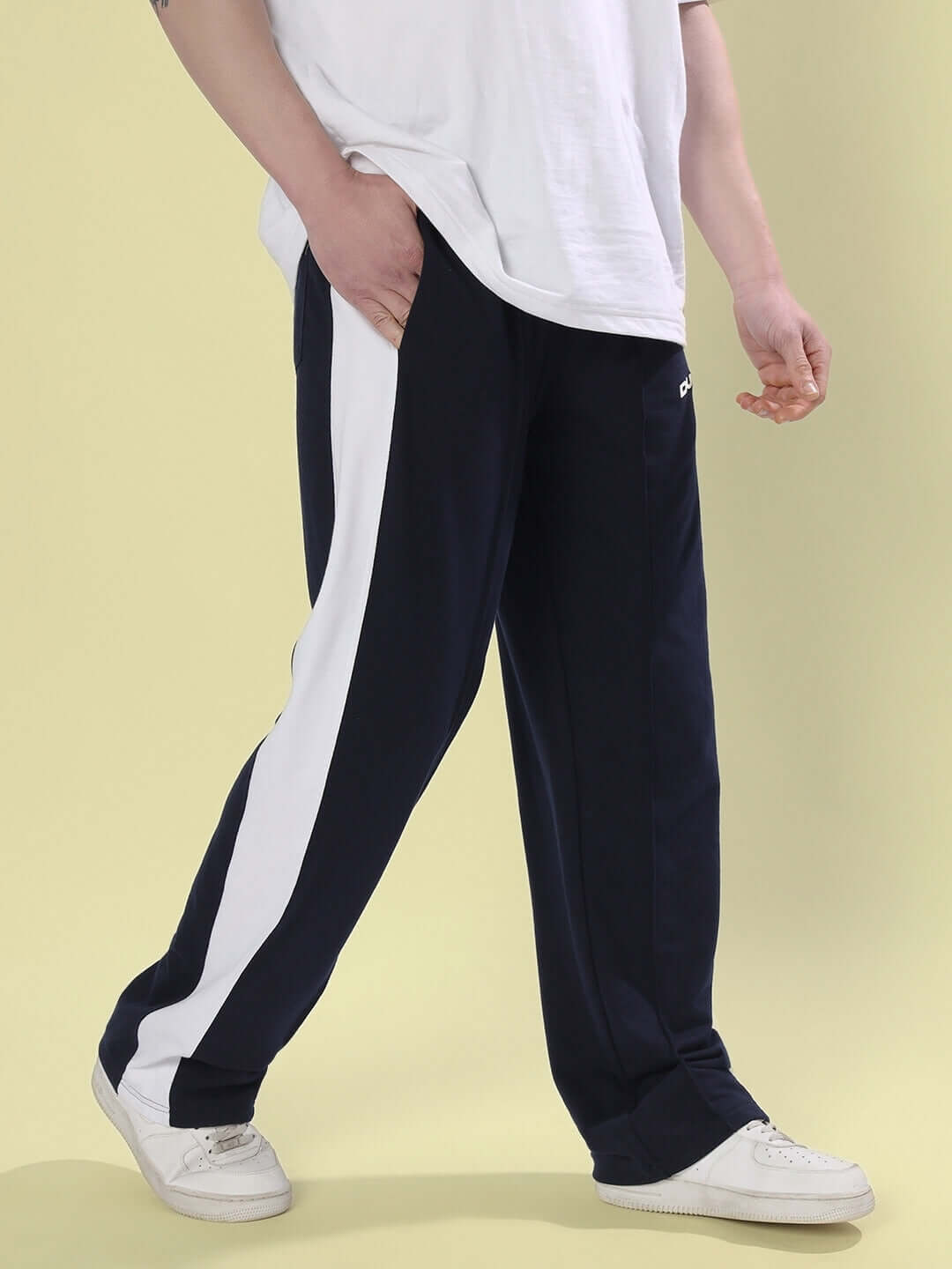 Person wearing navy blue side seam plated joggers with white stripe, showcasing a relaxed fit, by DUDS.