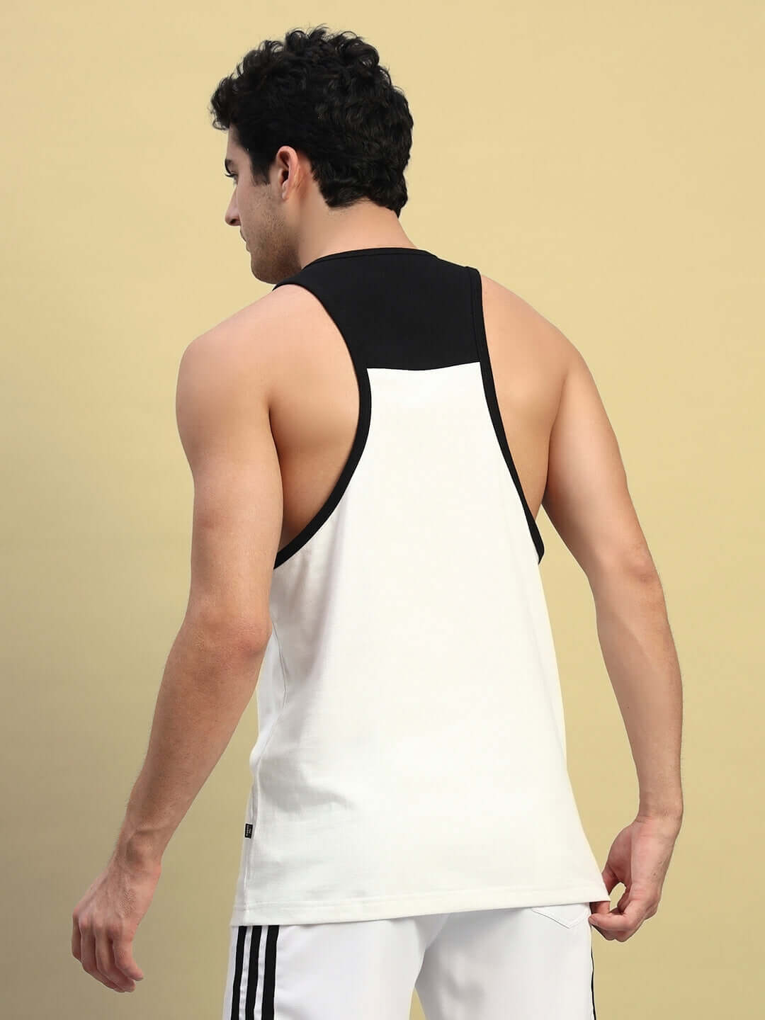 Back view of a man wearing an off-white NEO gym t-shirt with black trim, highlighting style and fit against a beige background.