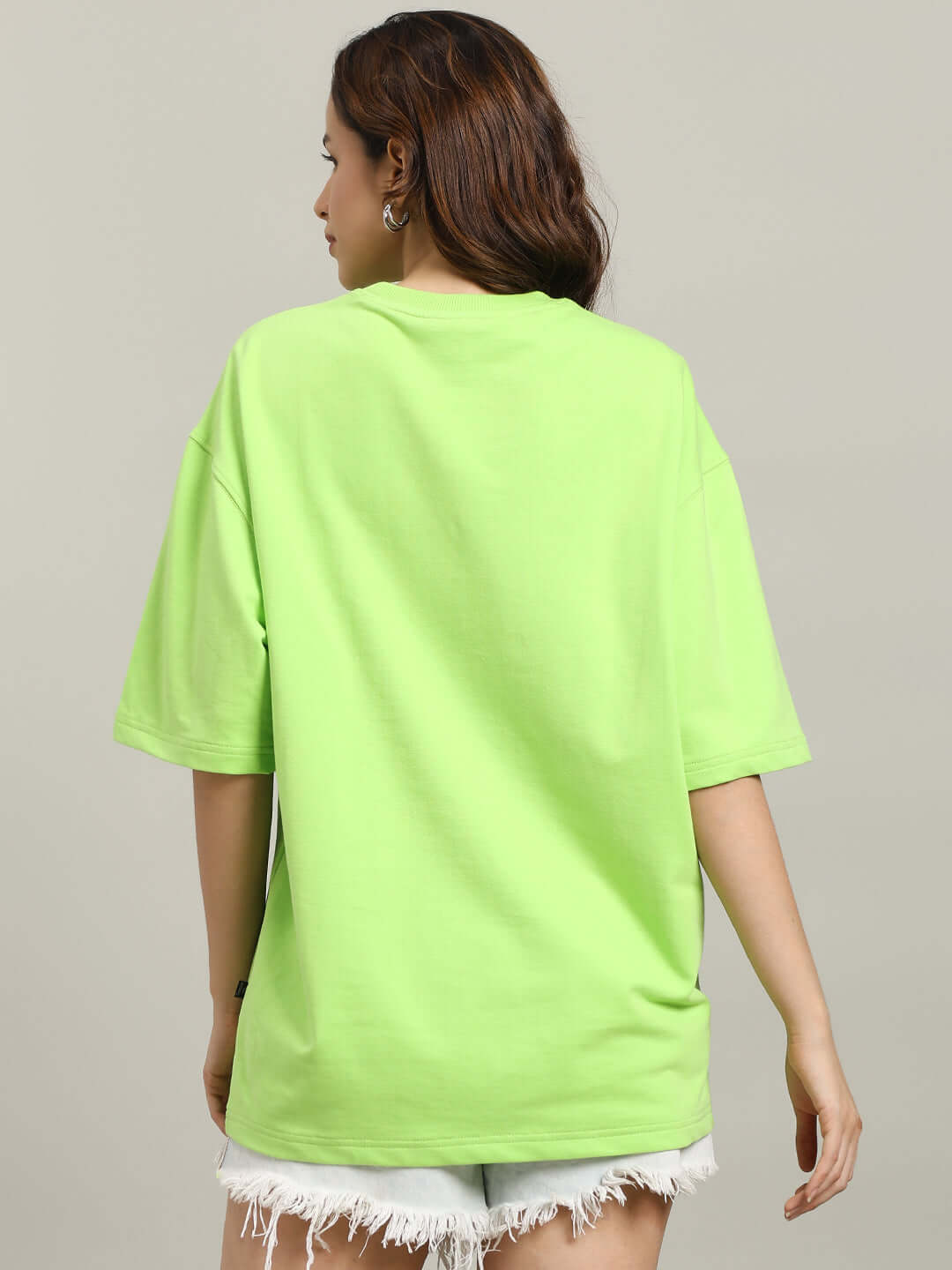 Back view of model wearing WOMEN'S ORCAS OVER-SIZED T-SHIRT NEON GREEN, showcasing vibrant streetwear style.