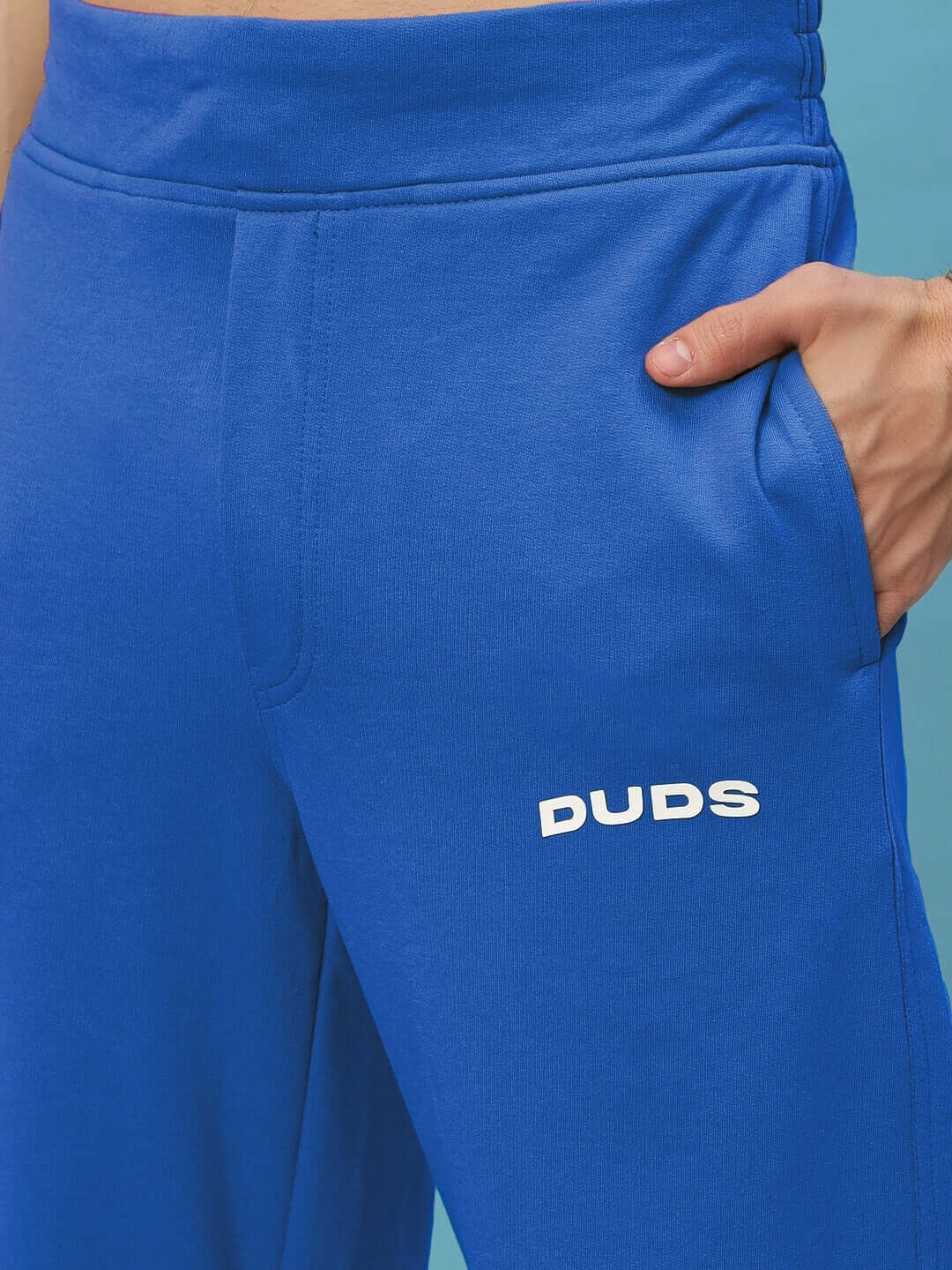 Man wearing New Era Relaxed Fit Joggers Royal Blue, showcasing side pocket and soft fabric texture.