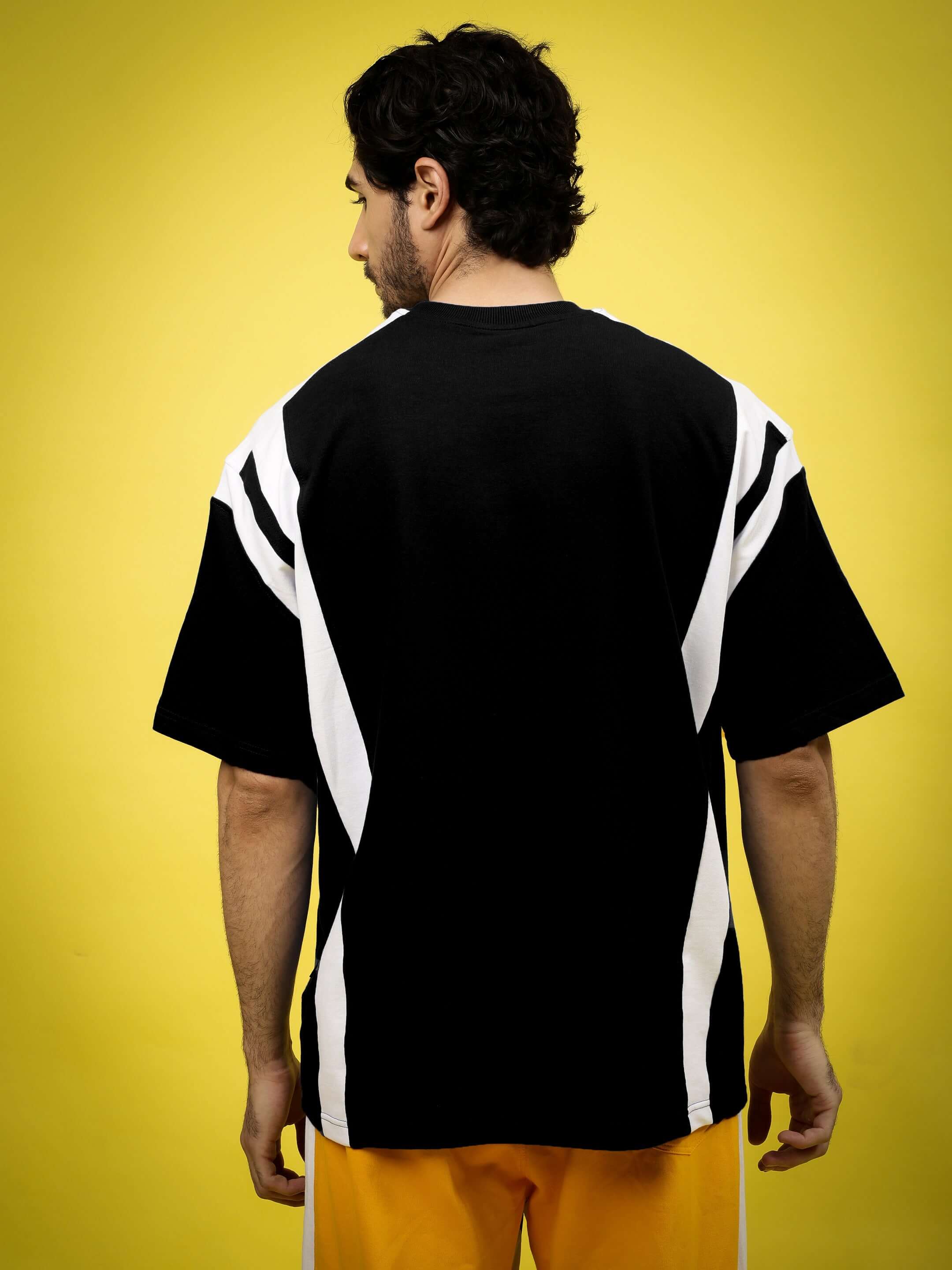 Back view of Ninja Storm oversized black T-shirt with white accents, made from premium cotton blend fabric, worn by a model against yellow background.