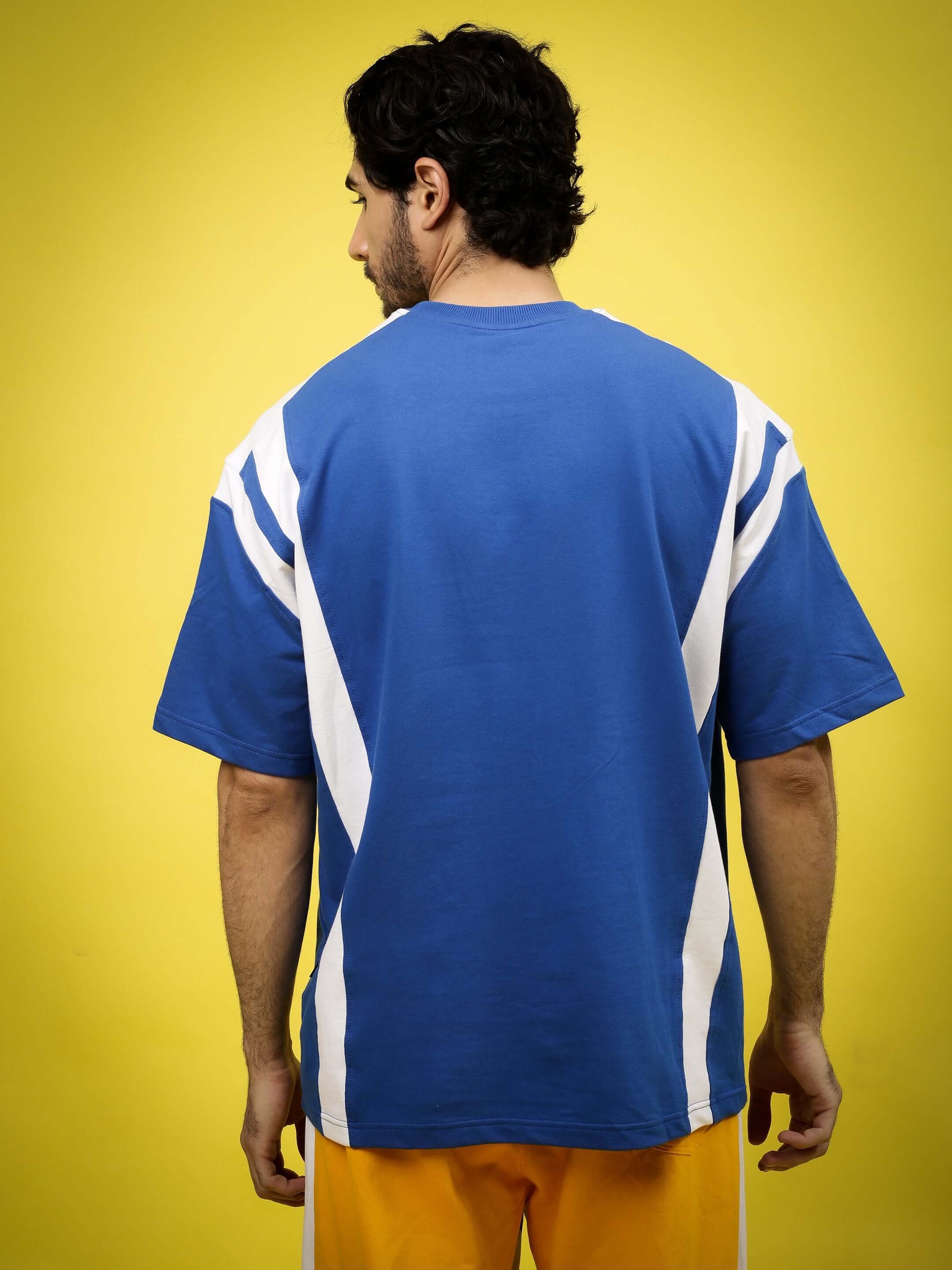 Man wearing NINJA STORM OVER-SIZED T-SHIRT ROYAL BLUE with white accents on yellow background, showcasing back design.